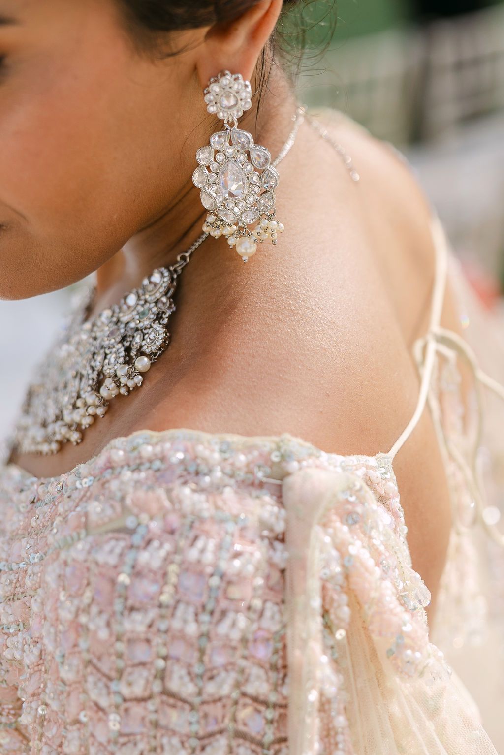 Close-up of sparkling crystal jewelry and delicate lace details on formal attire.