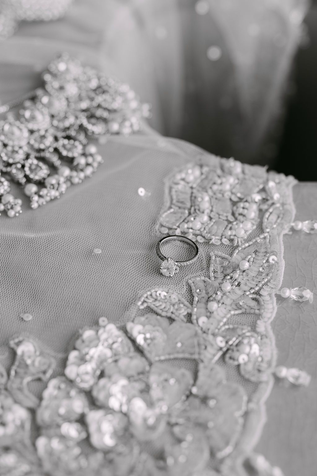 Close-up of sparkling diamond jewelry and wedding rings arranged on a gray surface.
