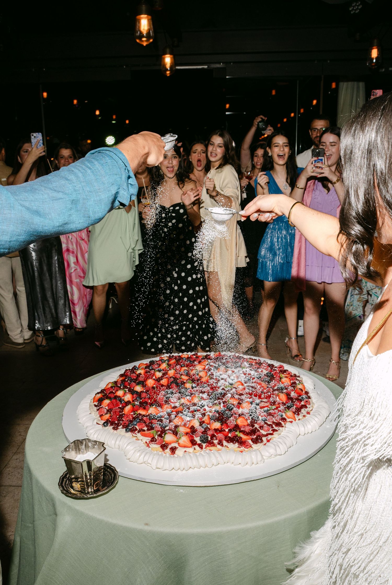 Large round dessert table decorated with fresh berries and whipped cream at an elegant event.