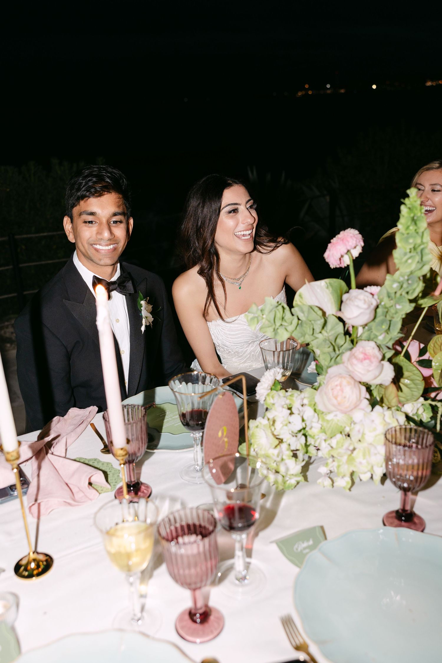 Elegant wedding reception table with pink glassware and lush floral arrangements.