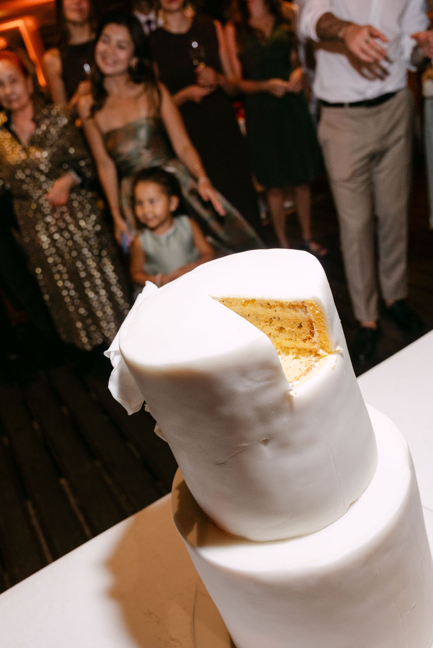 A sliced white wedding cake reveals its golden interior layers.