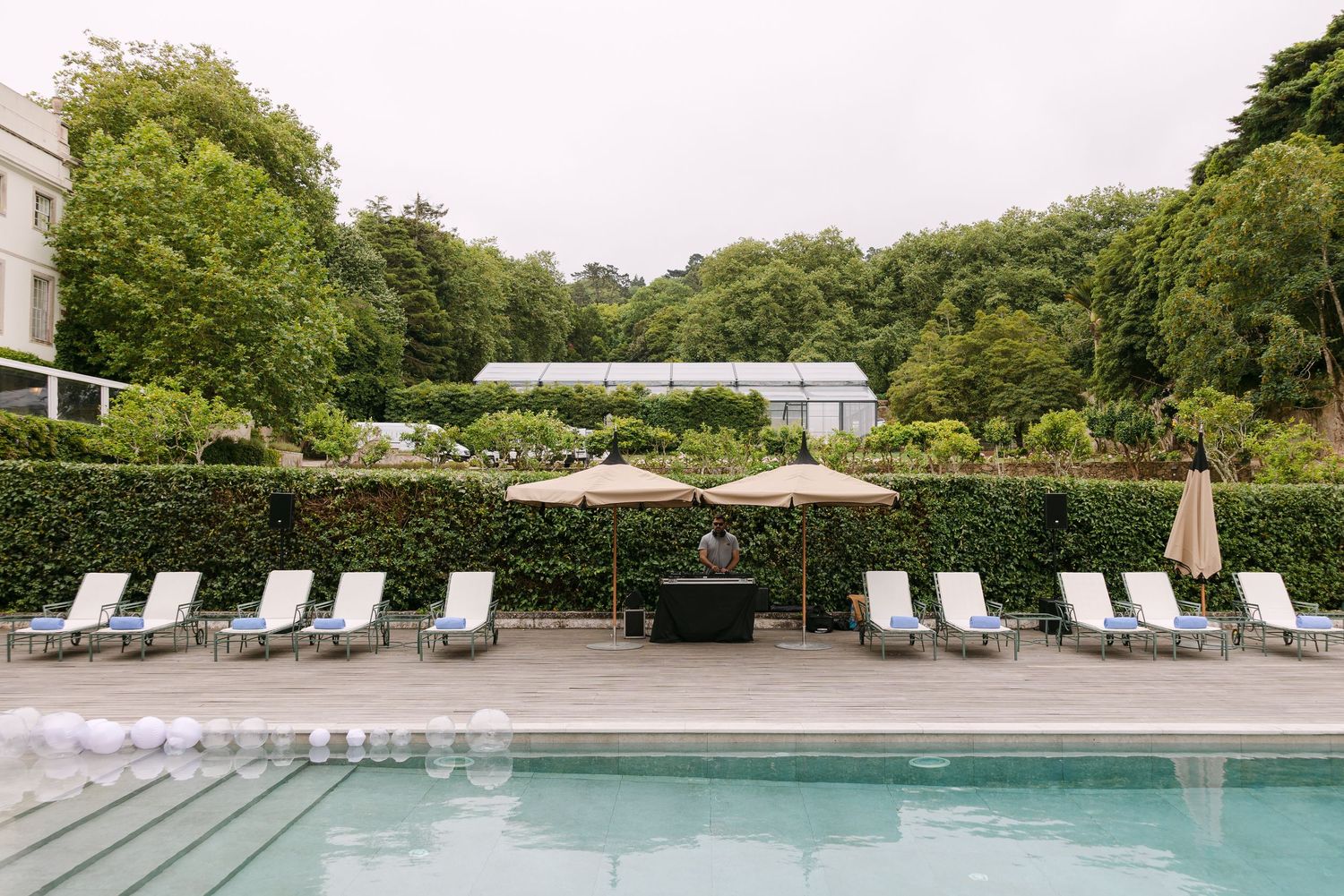 White lounge chairs line a poolside terrace at an elegant venue.