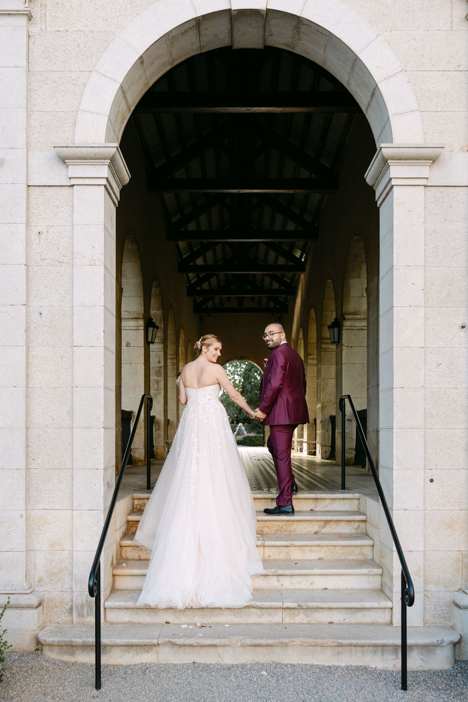 A romantic first look moment under stone archways at an elegant wedding venue.