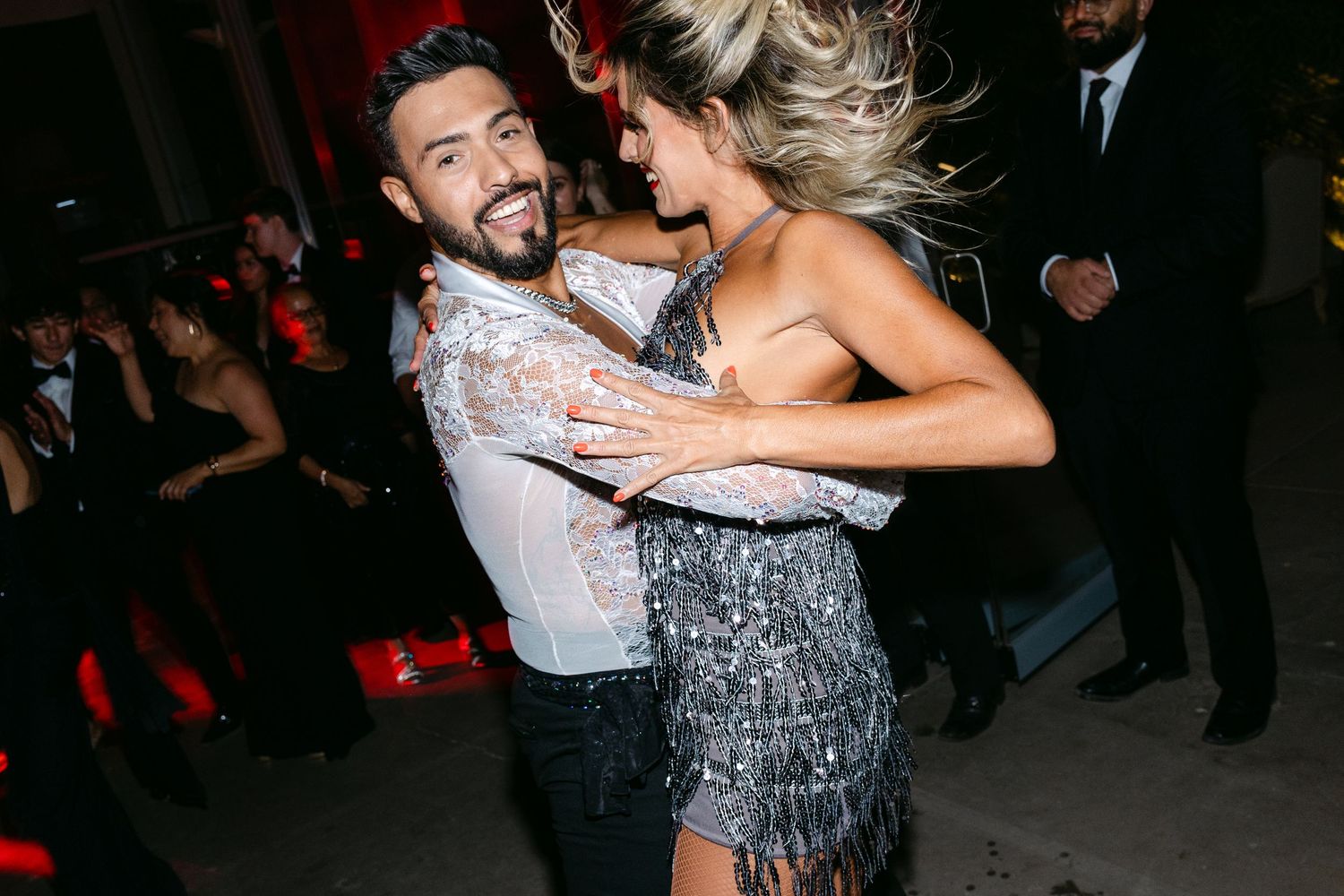 Energetic dancers performing dramatic dips and spins on a dark dance floor.
