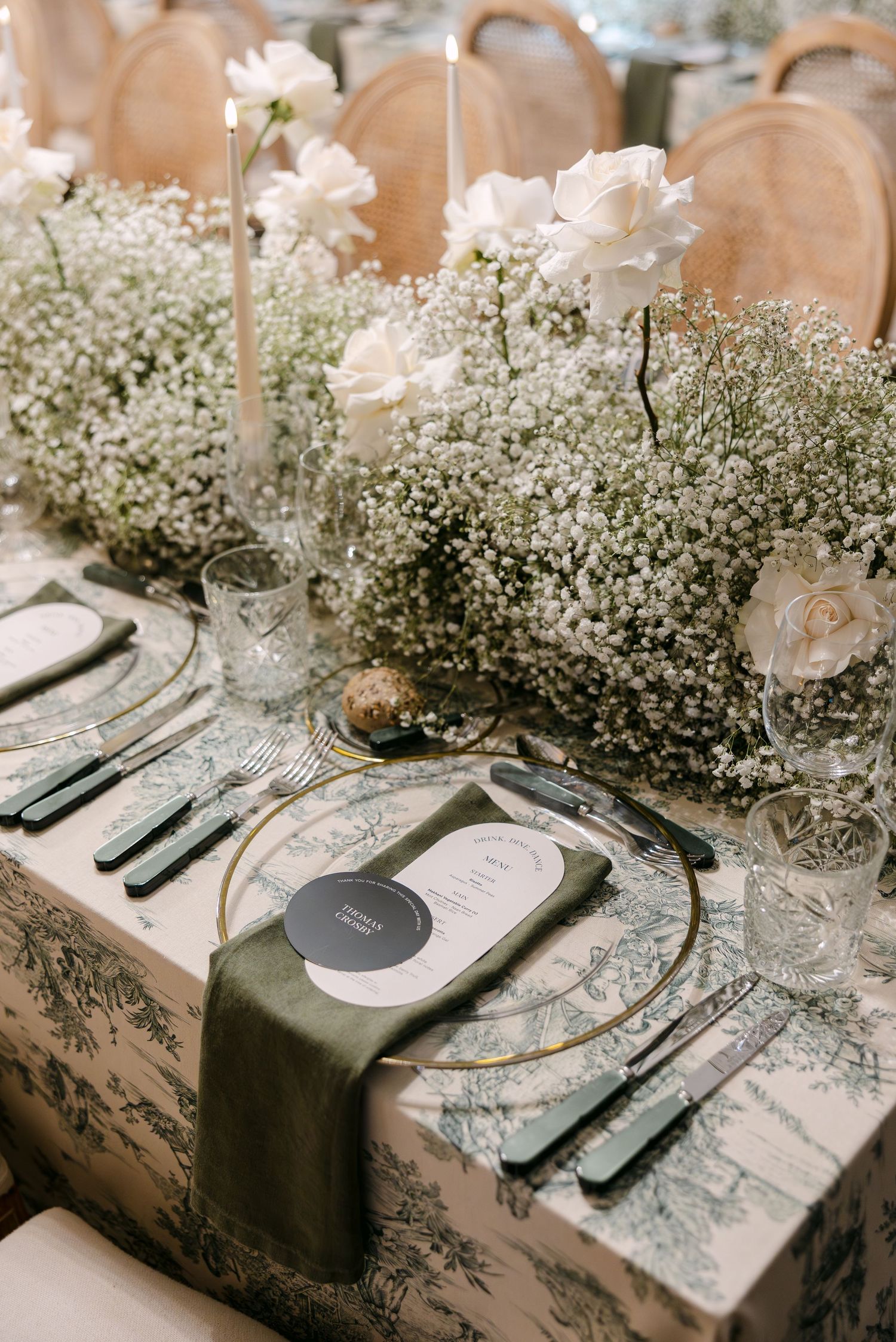 Romantic table setting with baby's breath centerpieces and elegant place settings on patterned linens.