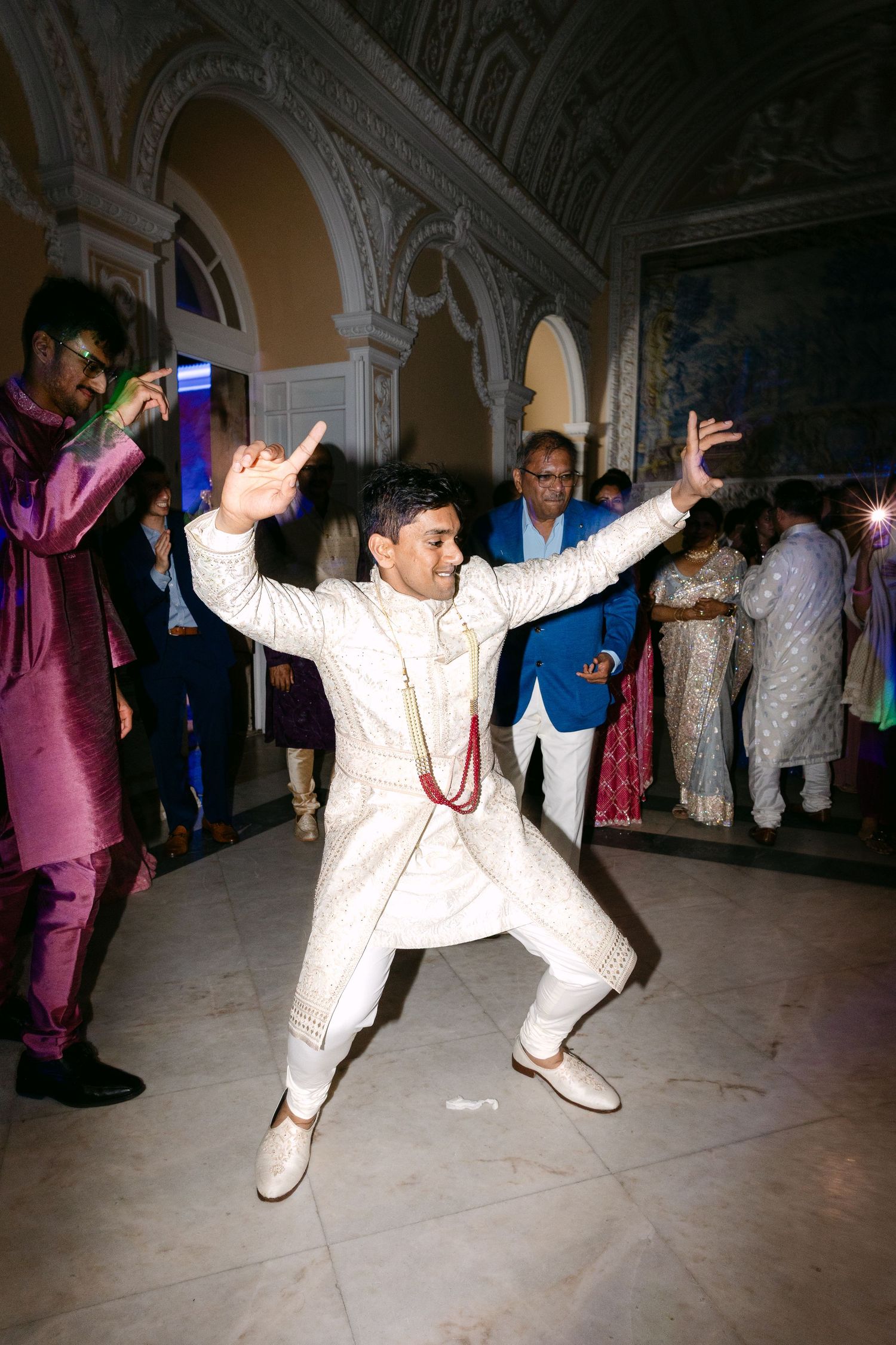 Energetic dance moves captured at a wedding reception in an ornate indoor venue.