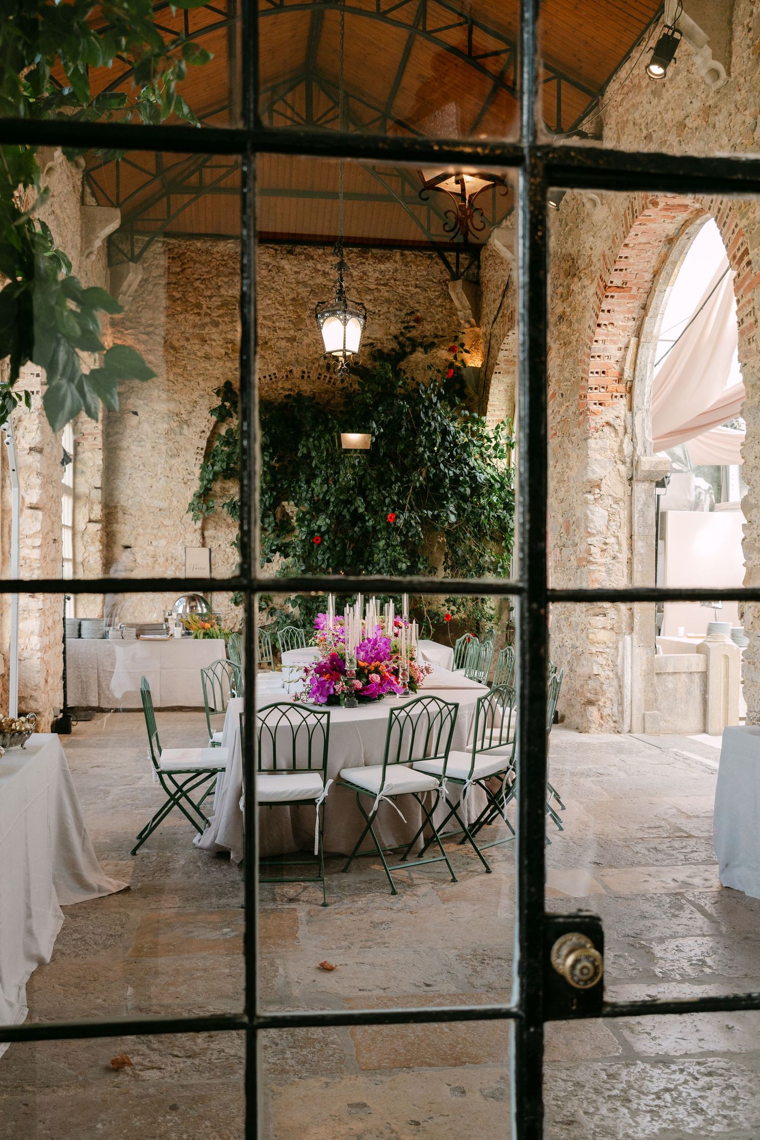 Stone archway corridor with hanging plants and dining tables set up for an elegant event.