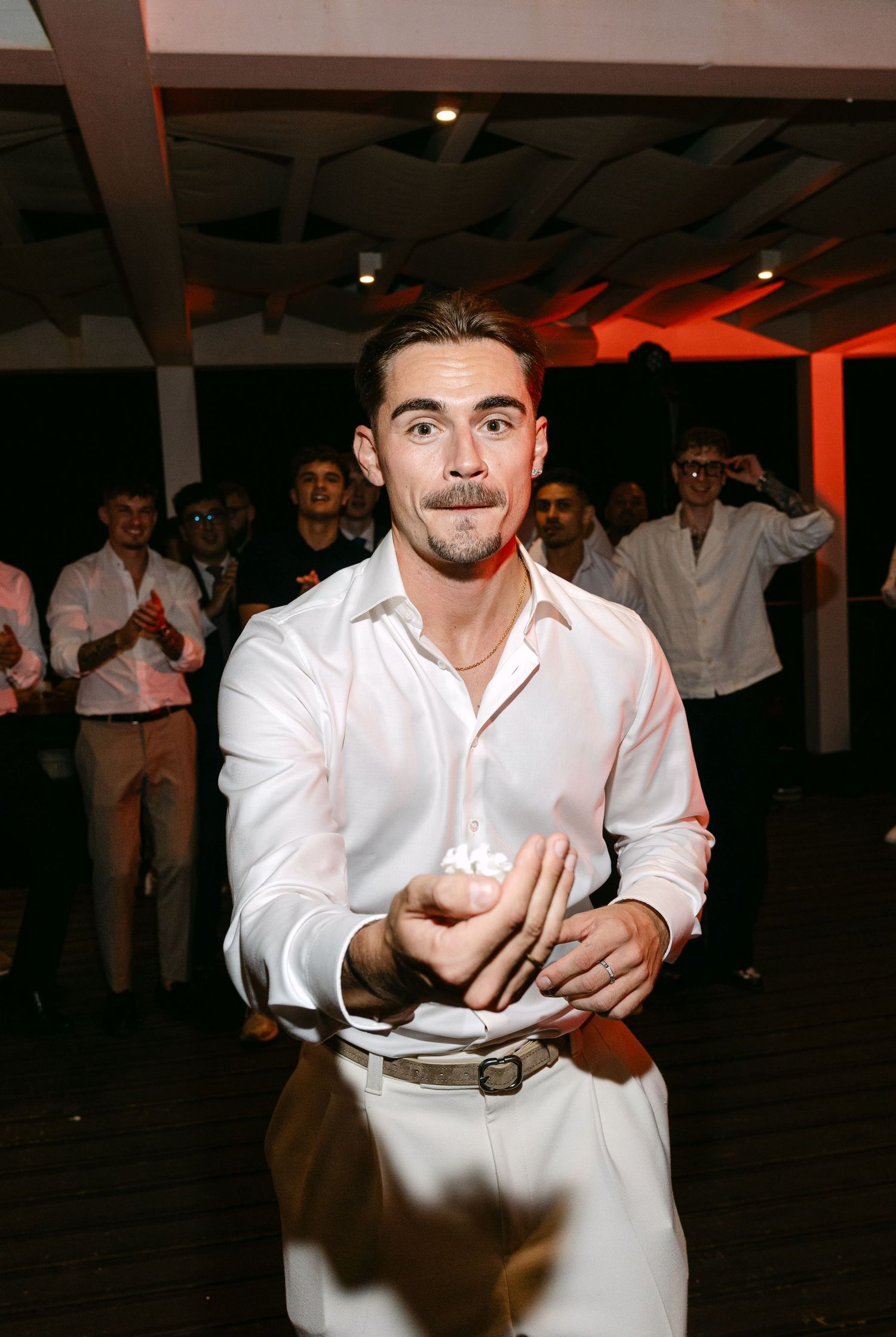 Man in white shirt dancing solo at wedding reception with crowd in background.