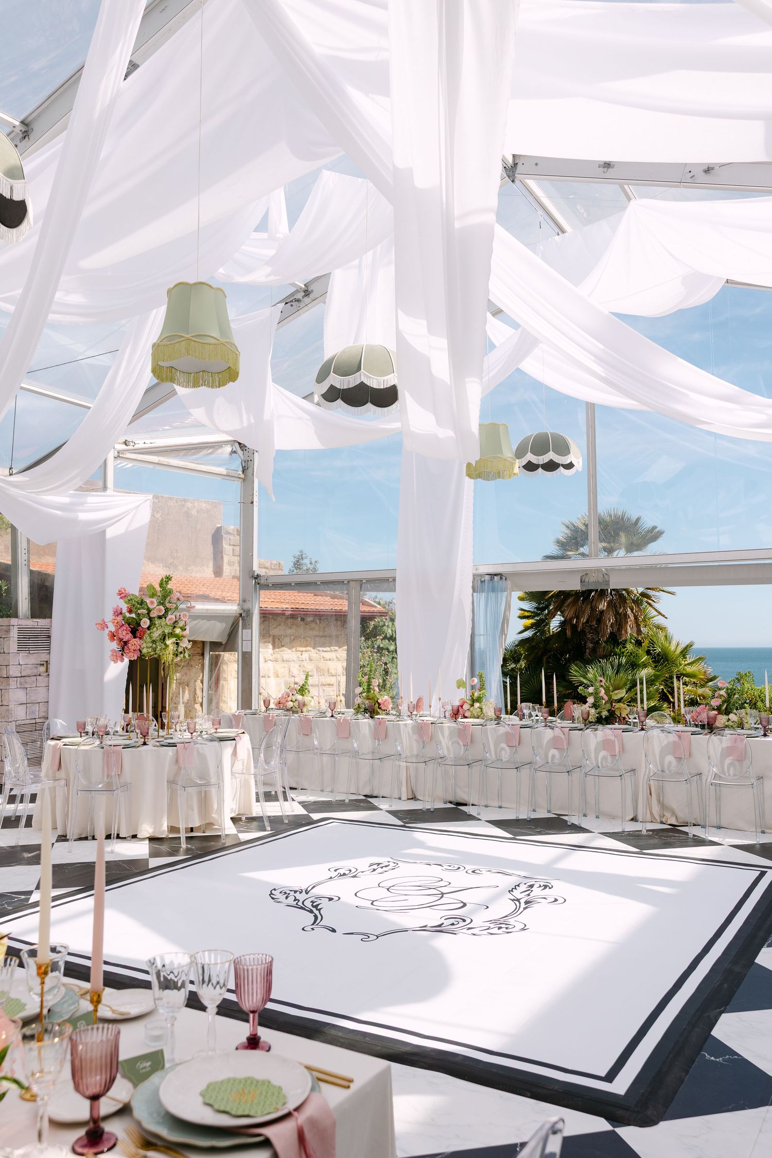 Elegant wedding venue with white draping, coastal views, and monogrammed dance floor.