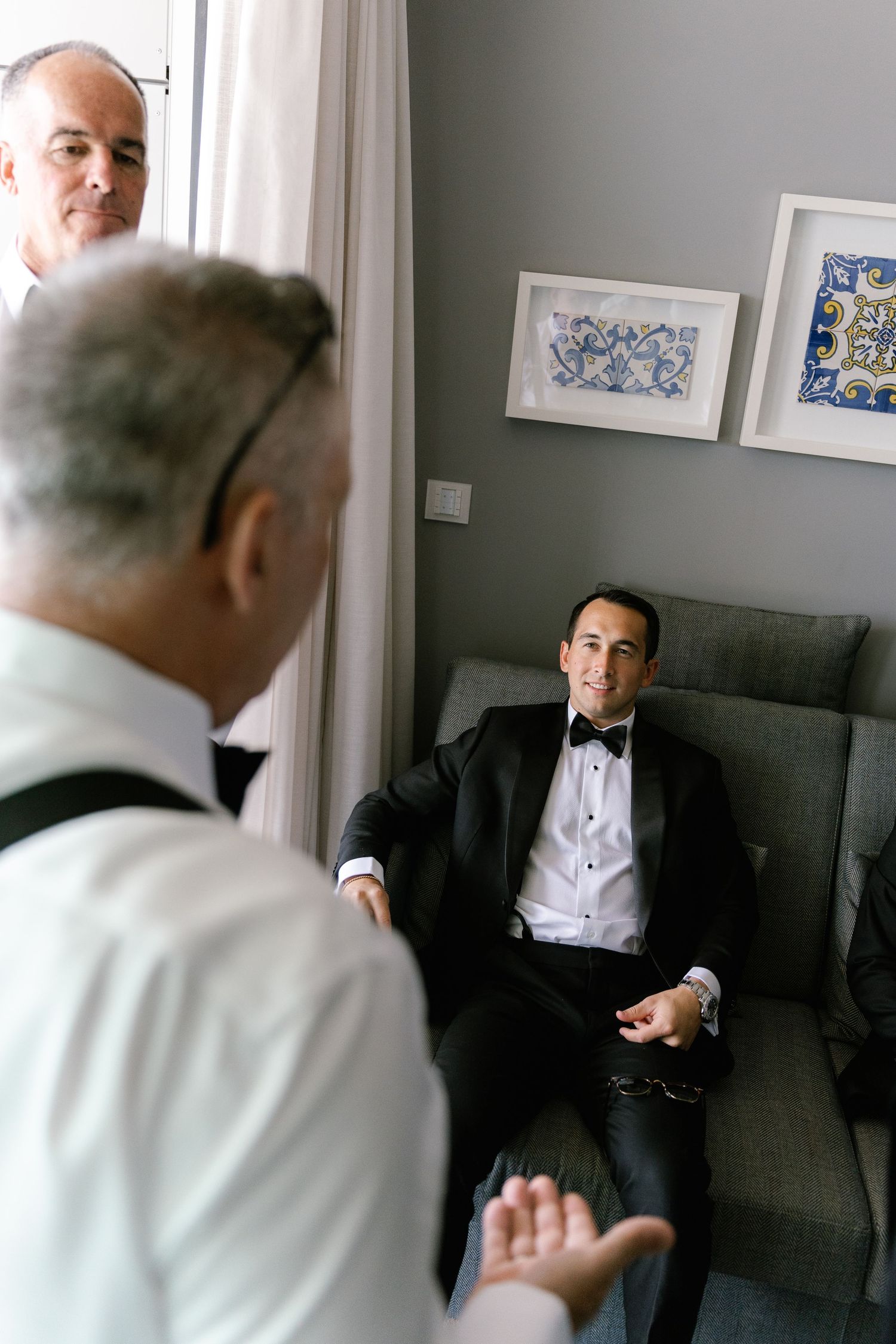 Wedding preparation scene showing interactions between people in formal attire in an indoor setting.