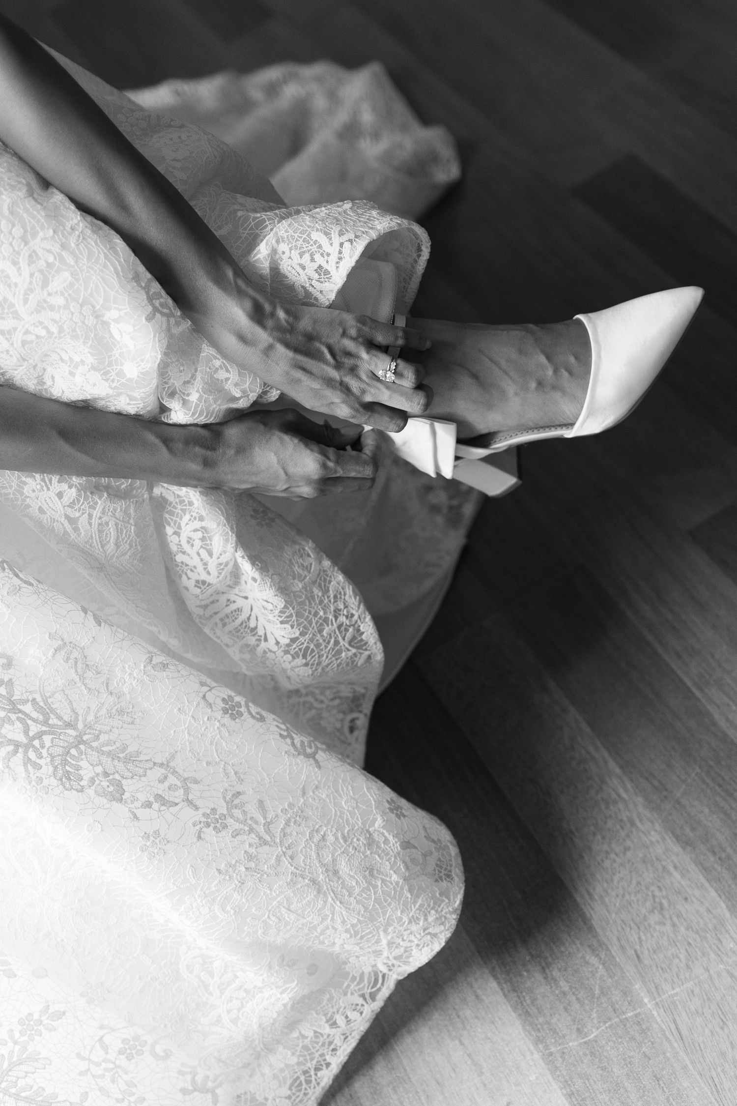 Detailed shots of delicate lace patterns on a wedding dress train laying on hardwood floor.