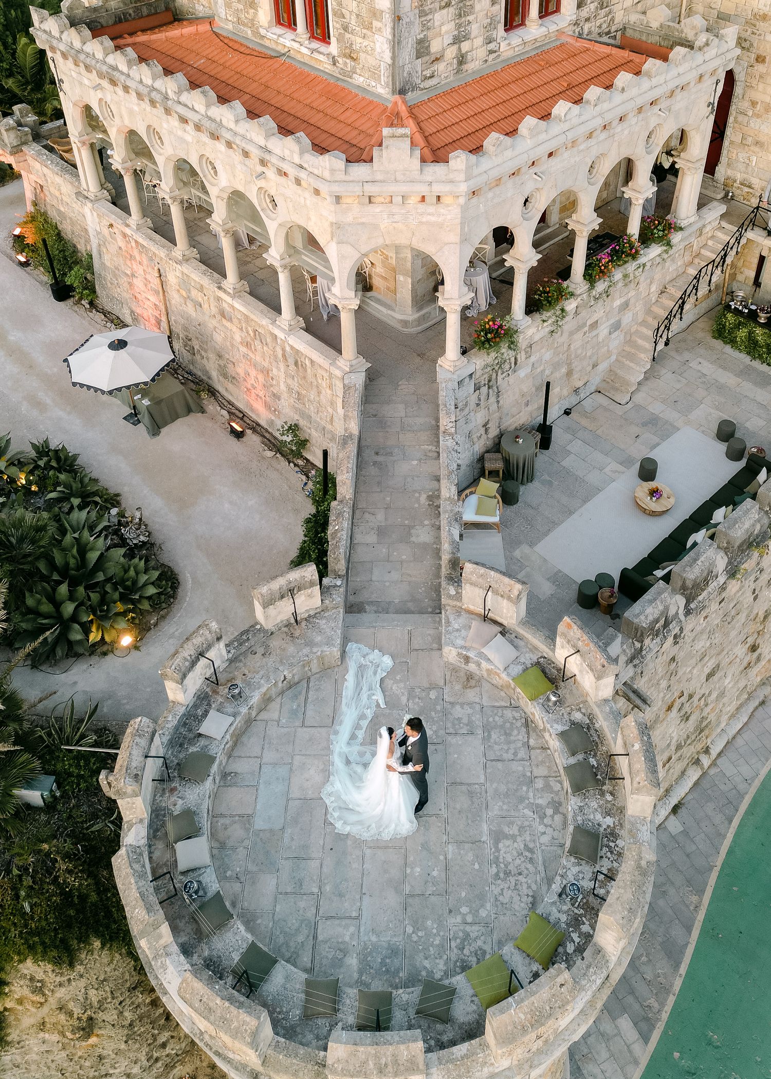 Aerial view of stone courtyard with wedding ceremony setup and decorative architecture.