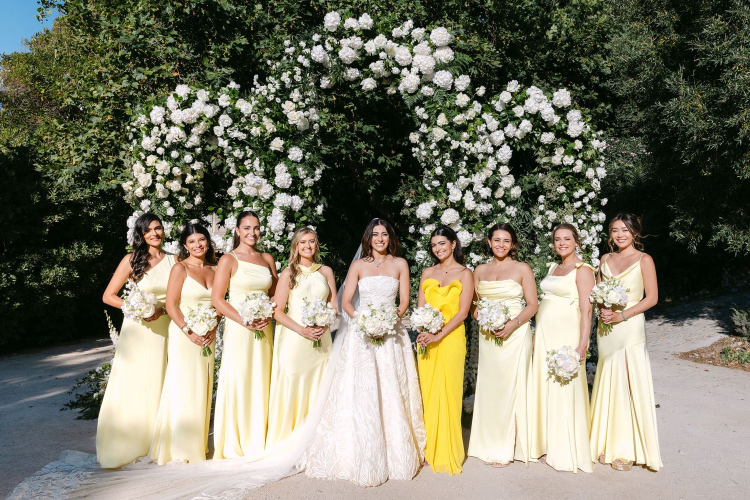 Wedding party members in pale yellow dresses lined up for a formal photo.