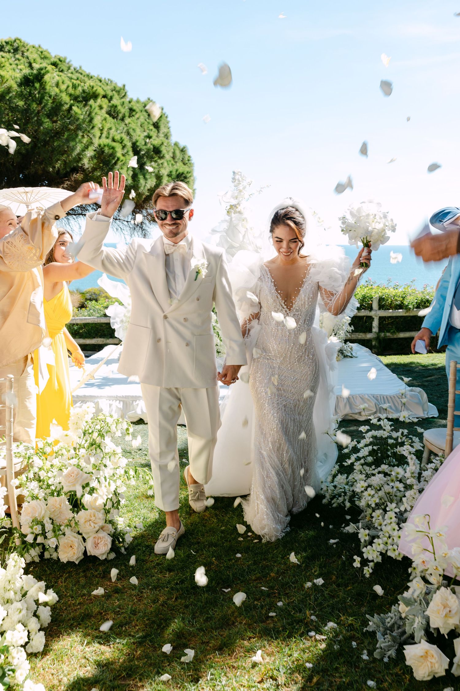 Wedding celebration with guests throwing flower petals in a garden setting.