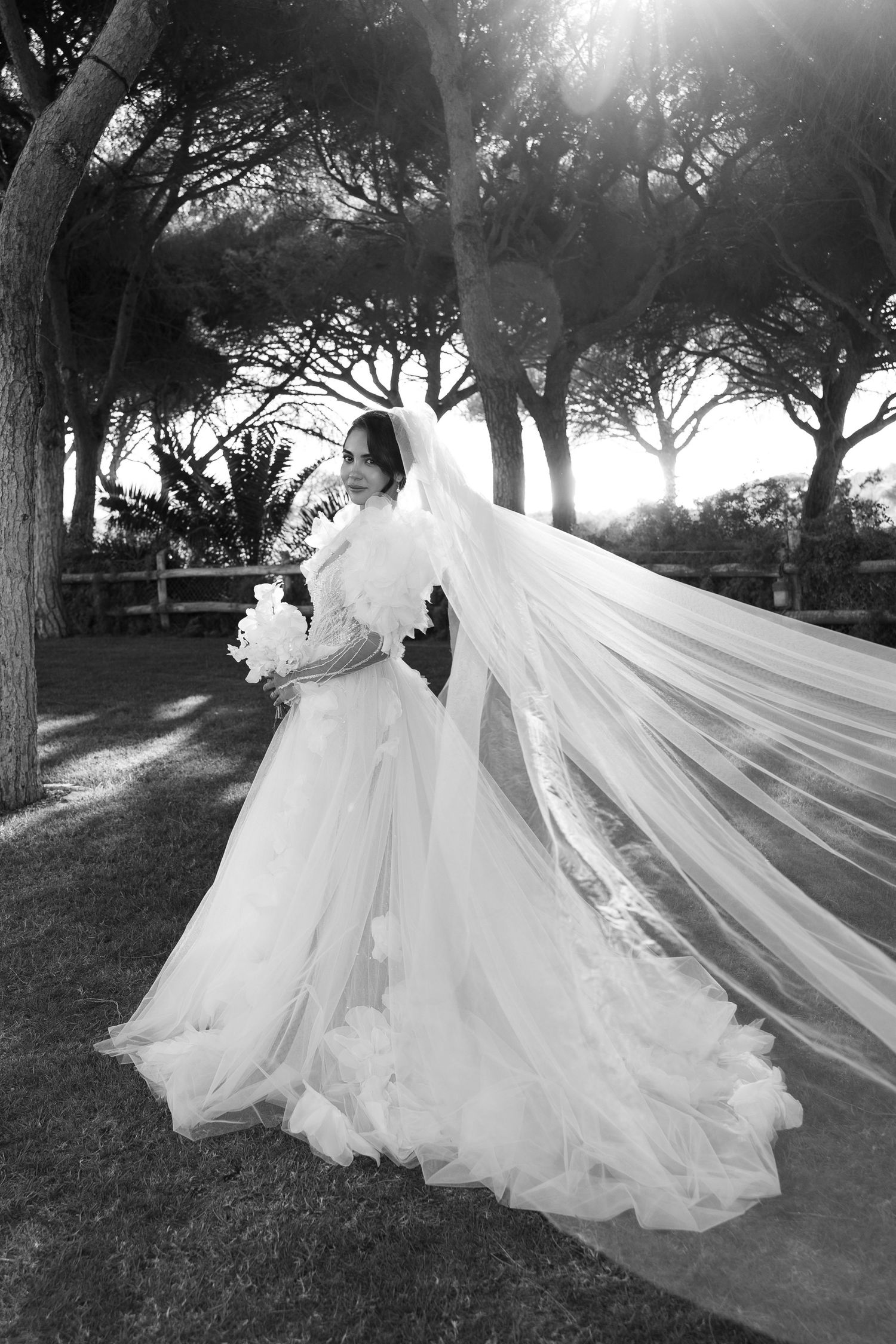A flowing white wedding dress and veil captured in dramatic black and white photography.