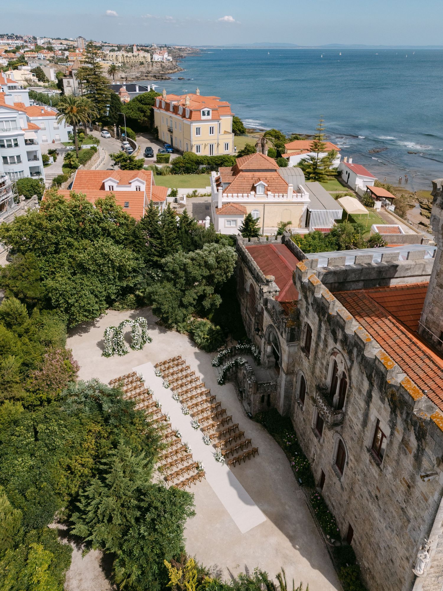 Aerial view of a coastal venue with red-roofed buildings and stone architecture overlooking the ocean.