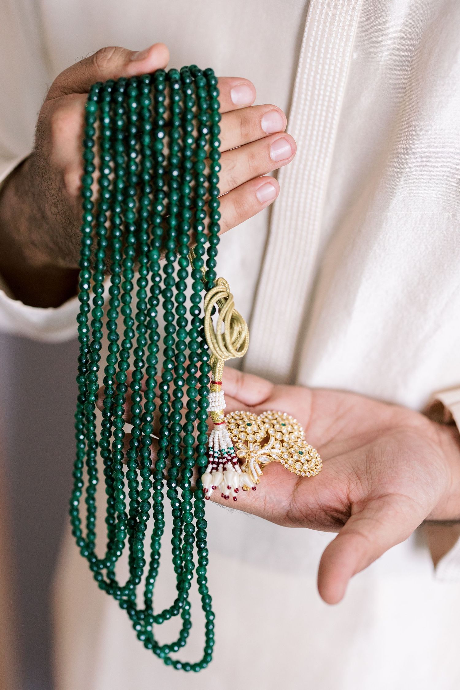 Emerald green prayer beads with gold accents displayed against white background.