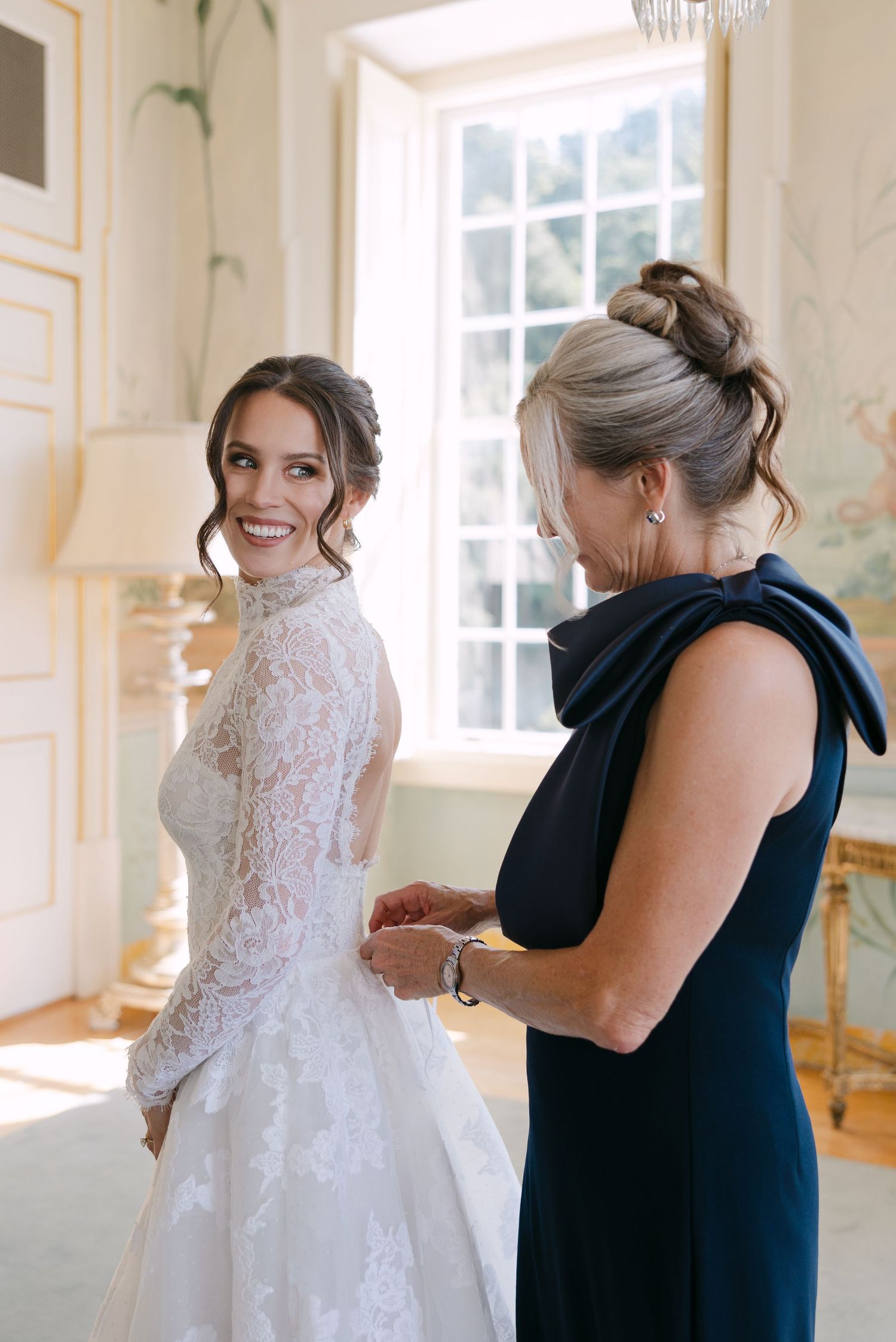 Getting ready scene in a sunlit room with ornate wallpaper and chandeliers.