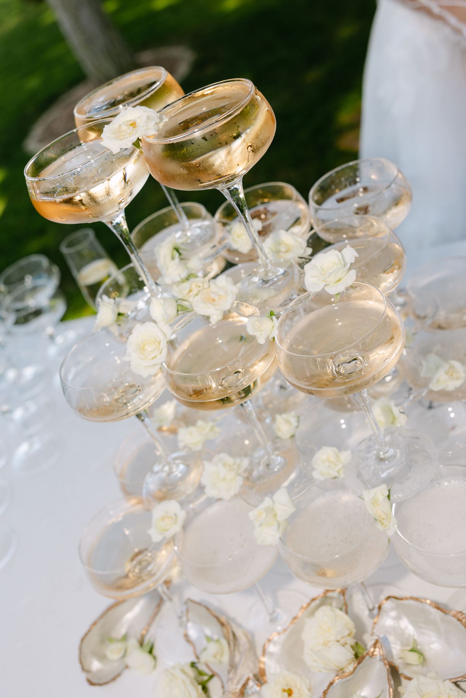 Elegant champagne coupe tower with delicate white flowers in natural light.