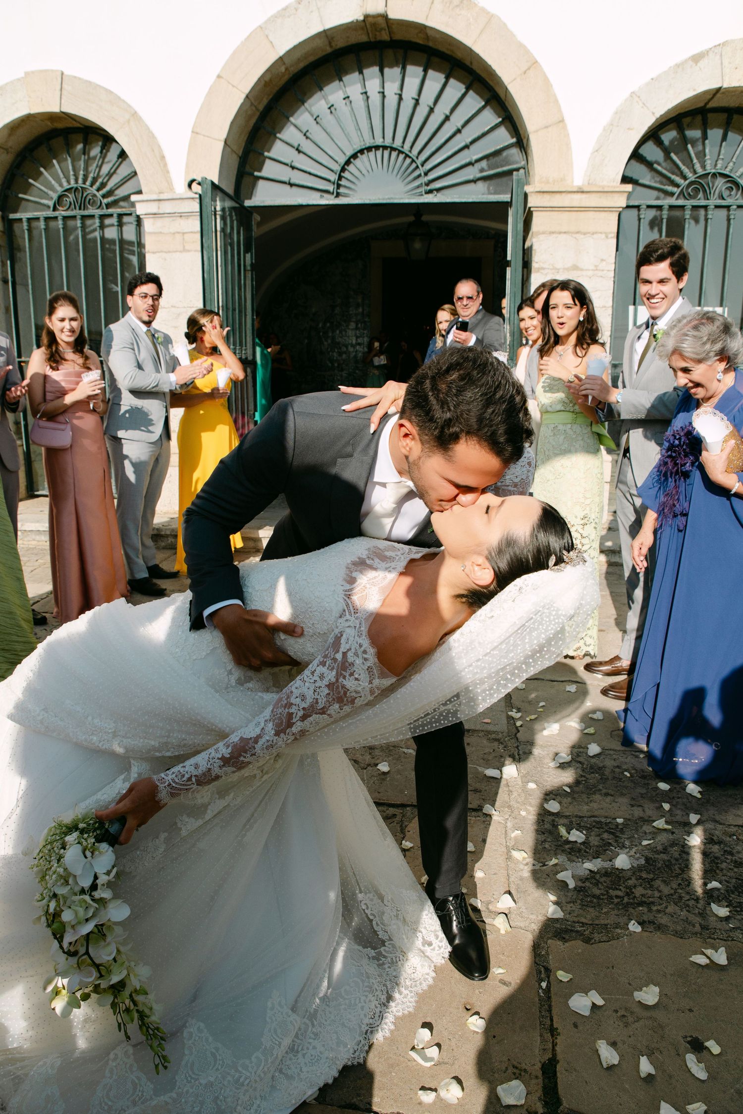 Newlyweds celebrating outside a historic building with ornate arched doorways.