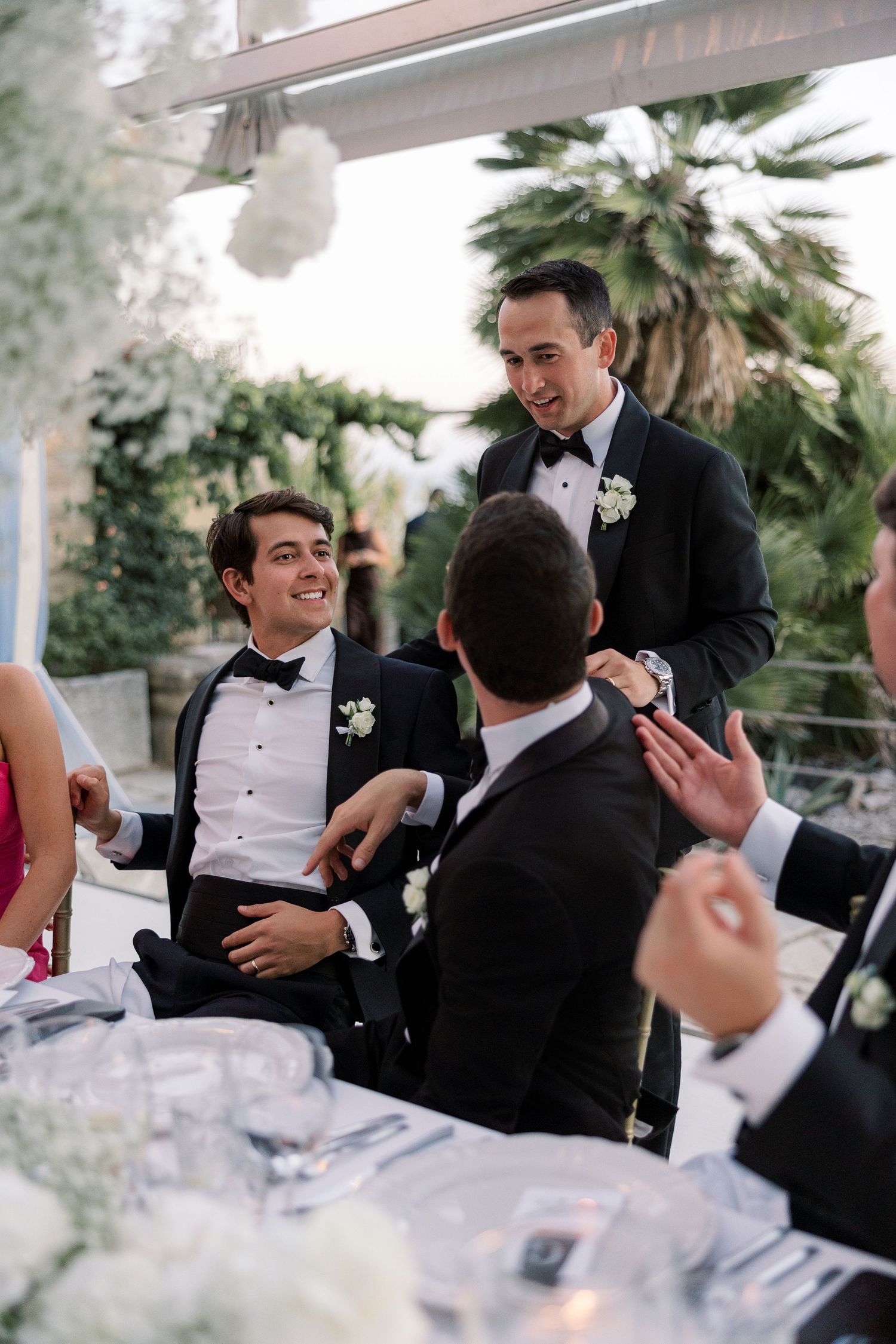 Wedding guests in formal attire laughing and celebrating at an elegant reception.