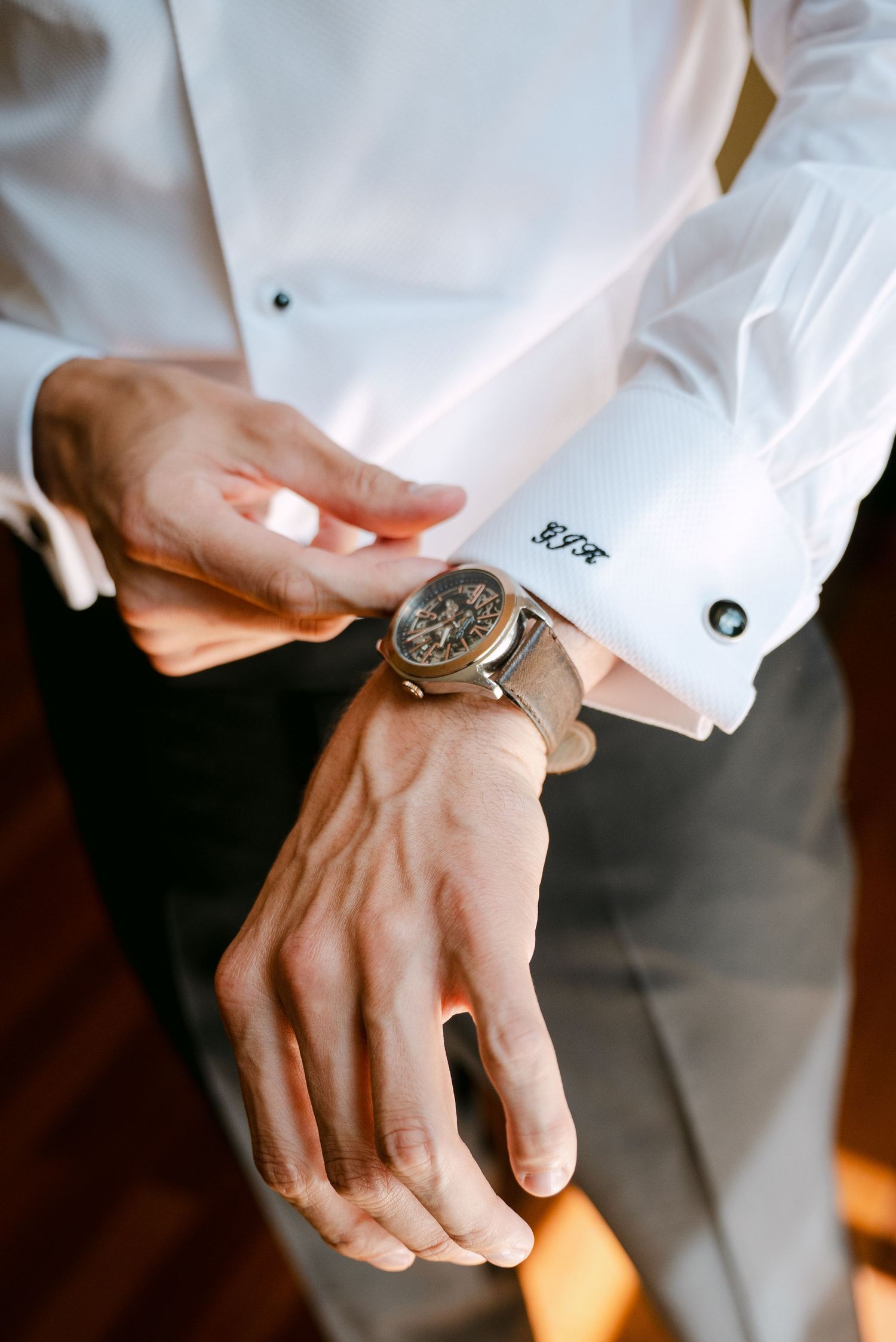 Detail shots of hands with a luxury watch wearing formal white dress shirt cuffs.