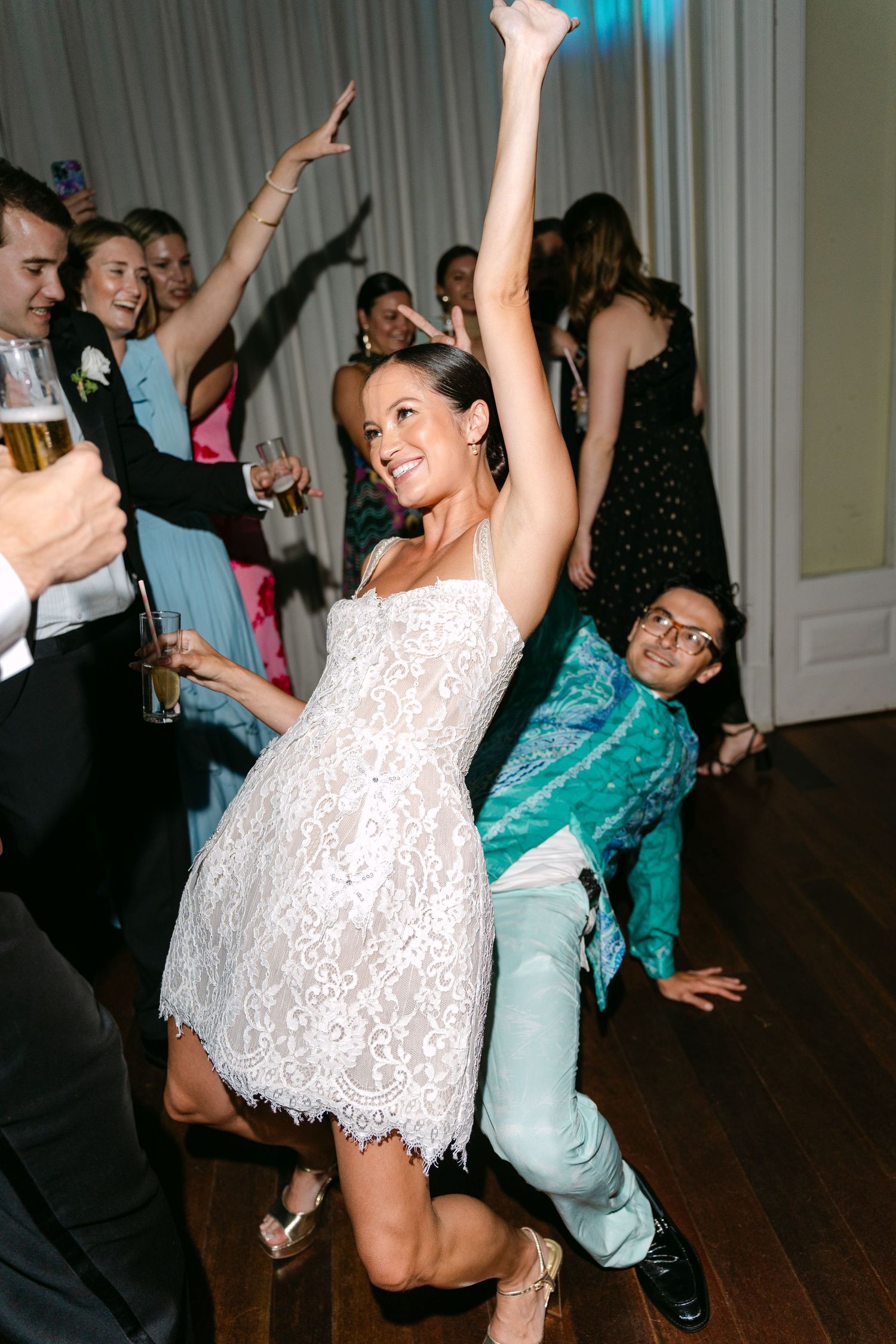 Energetic dance party moments captured at a wedding reception with colorful lighting.