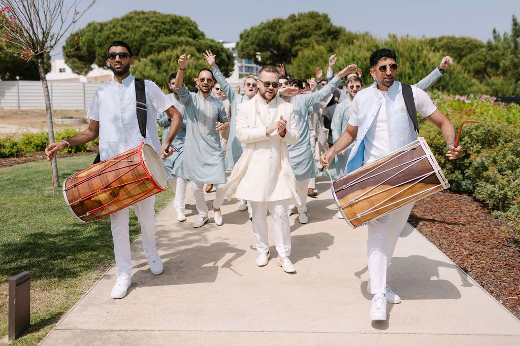 Traditional drummers in white outfits perform during an outdoor cultural celebration.