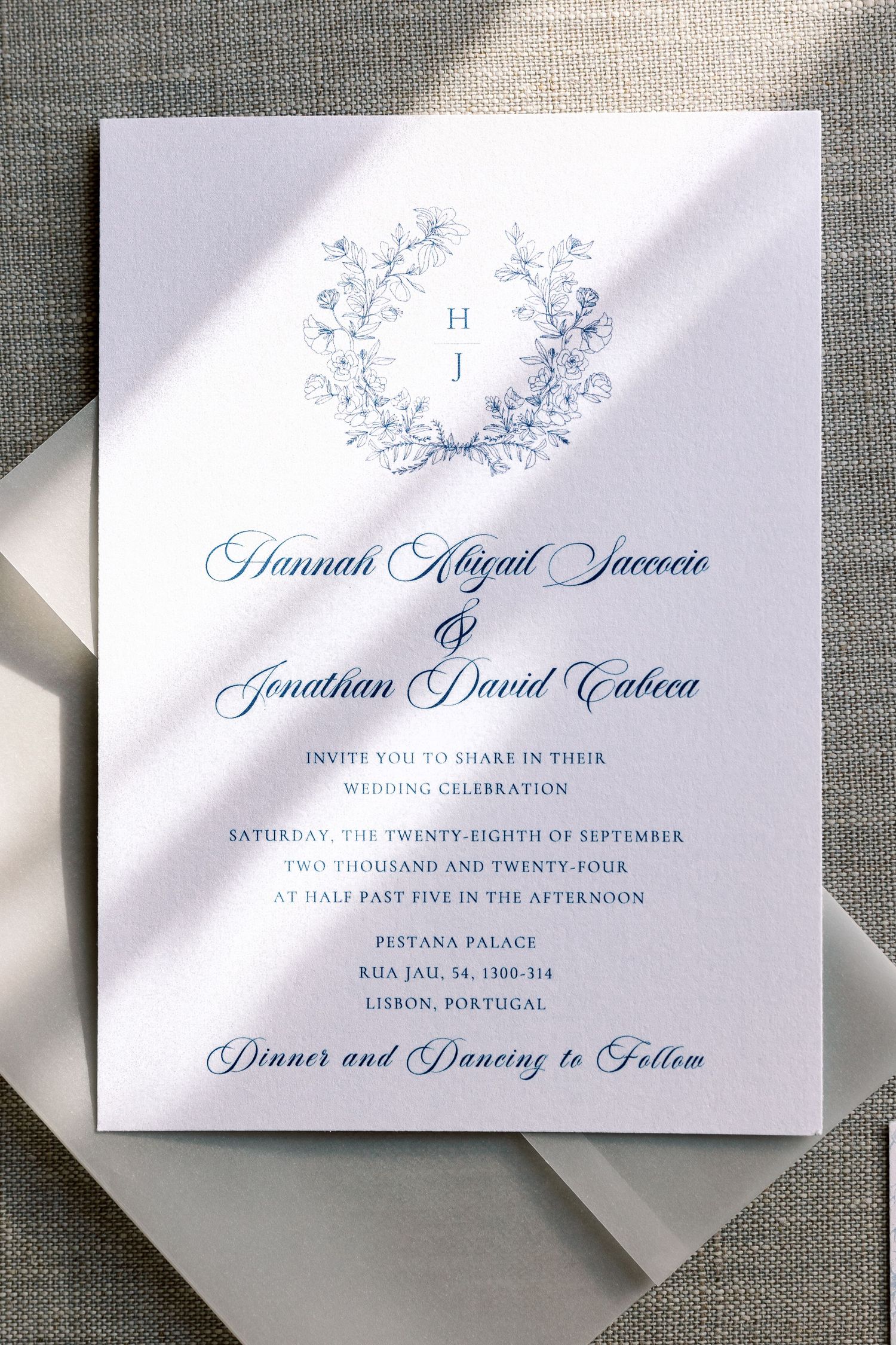 Elegant wedding invitation with blue calligraphy and floral details in natural lighting.
