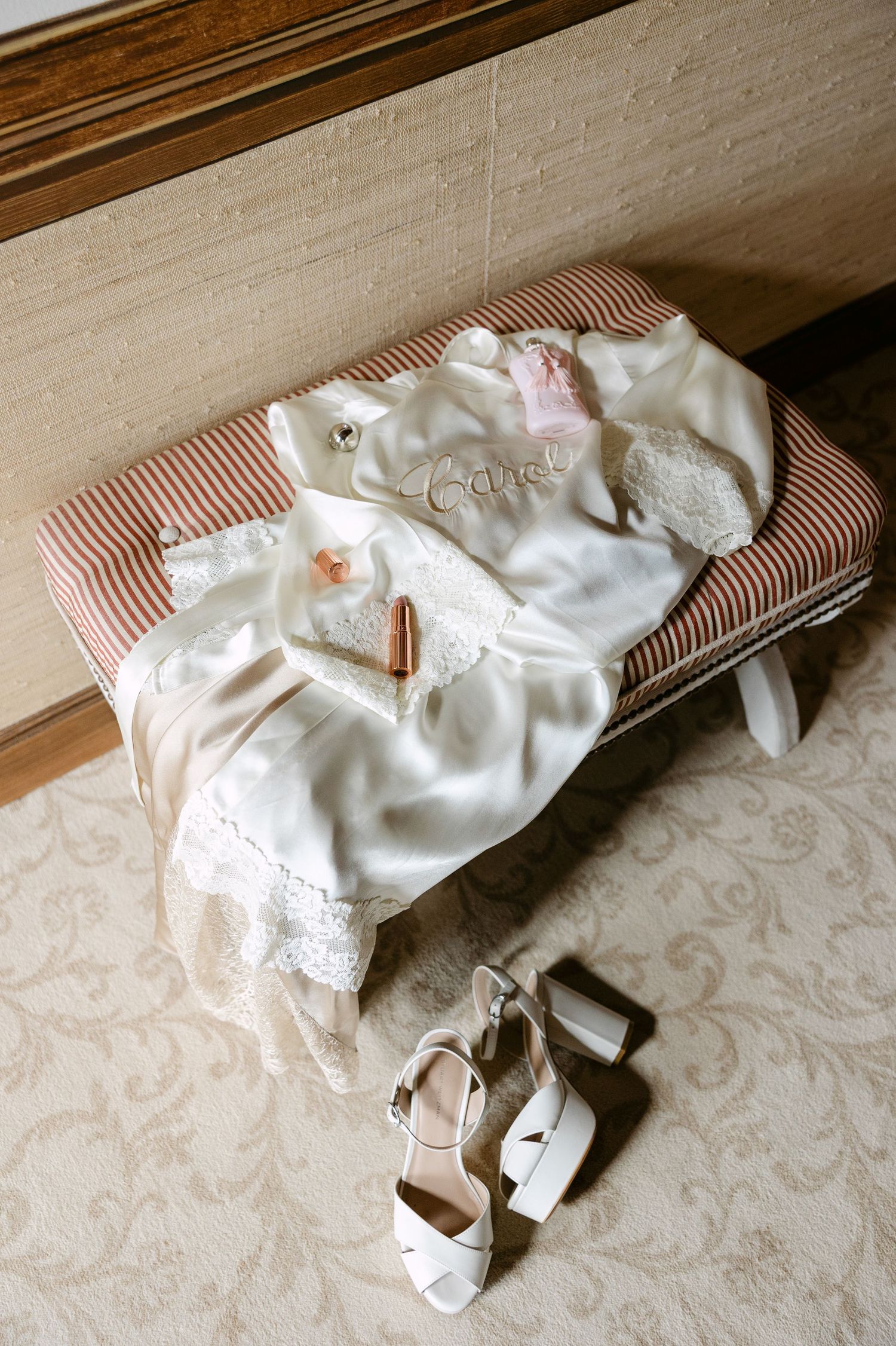 Wedding dress and accessories laid out on a decorative bed covering.