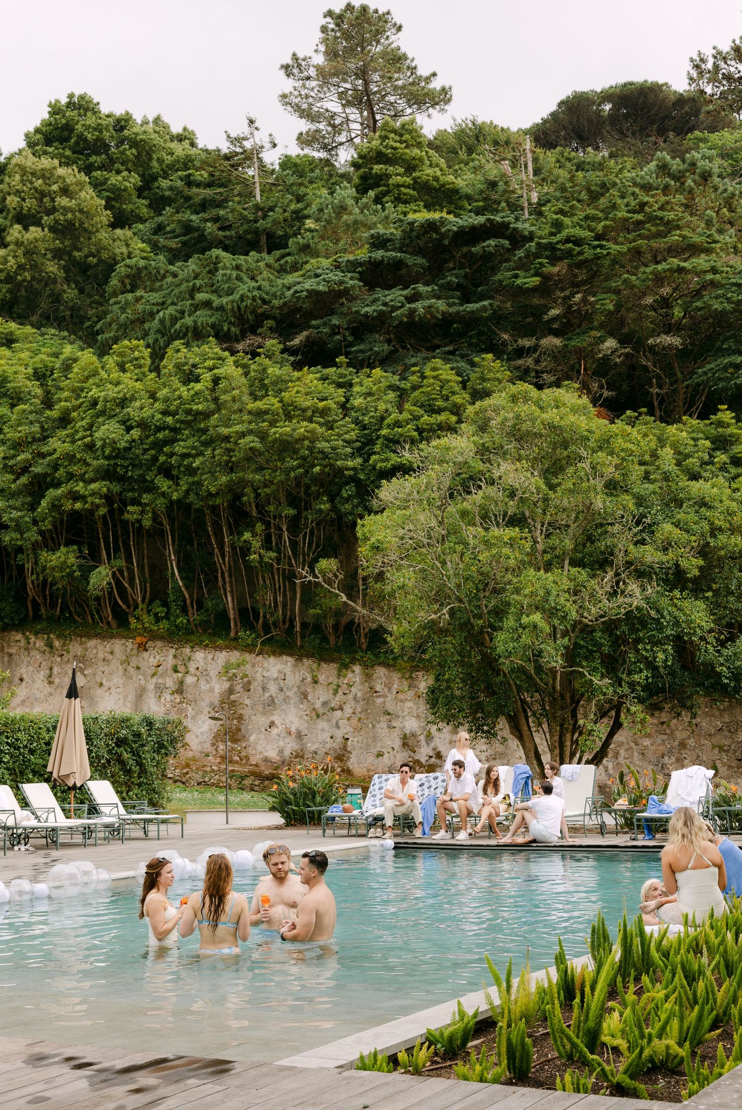 Wedding guests enjoying a luxurious outdoor pool surrounded by lush greenery.