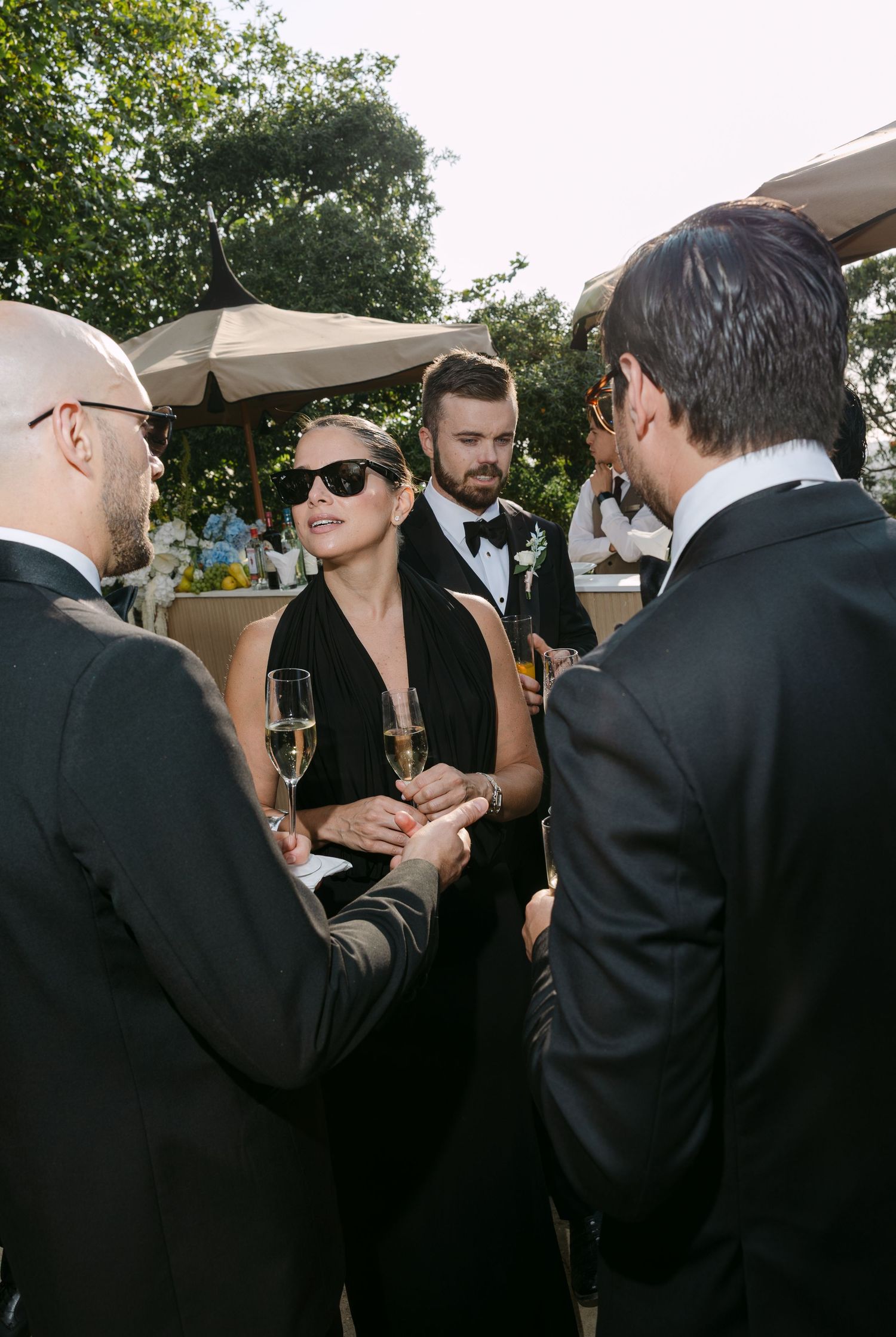 Wedding guests in formal attire gathered outdoors during reception celebration.