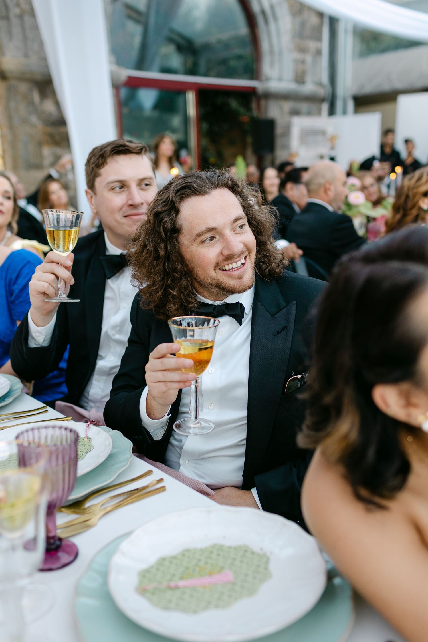 Wedding guests raise champagne glasses during a celebratory toast at an elegant reception.