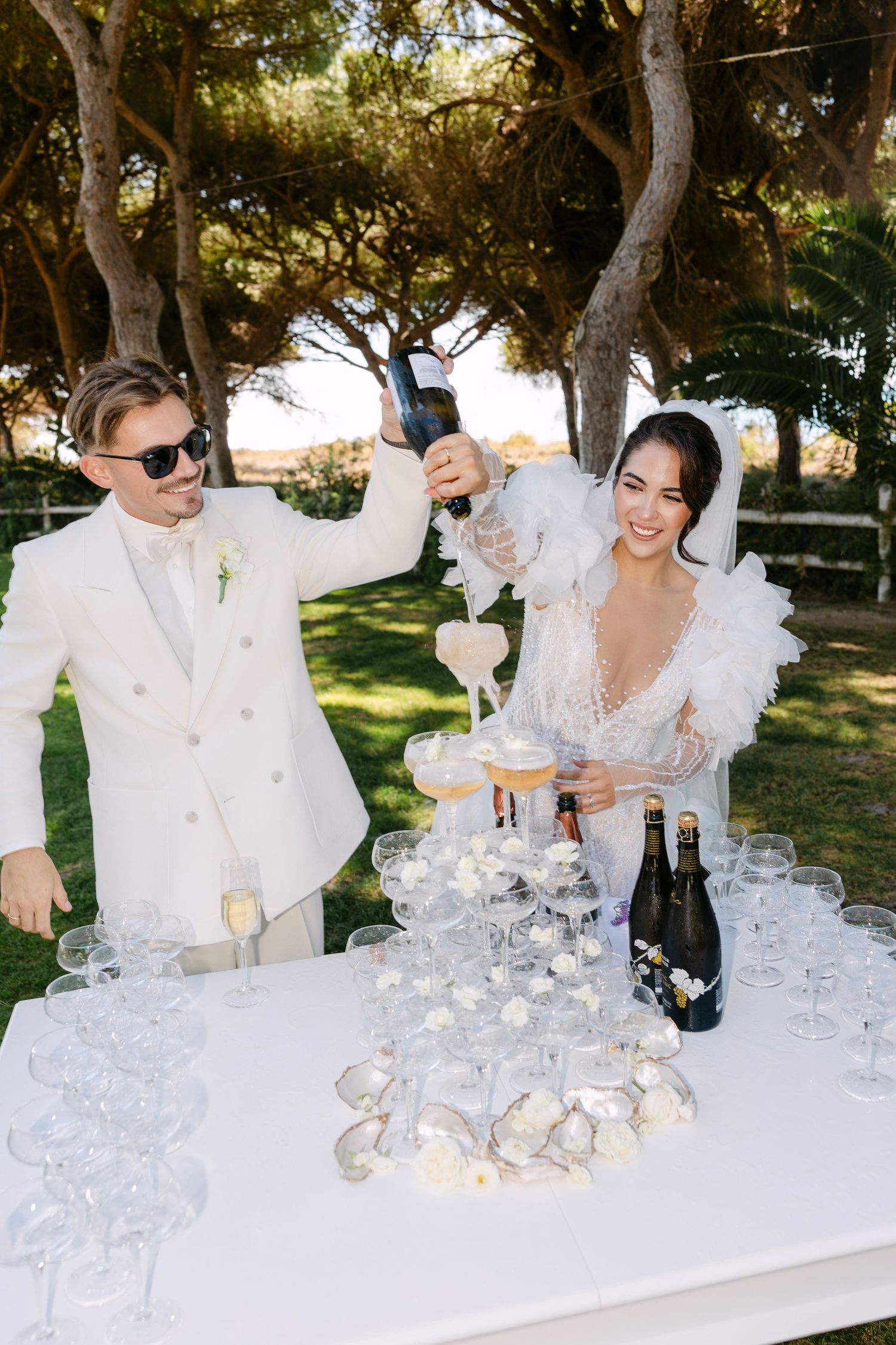 Wedding celebration with champagne tower and glasses being poured outdoors.