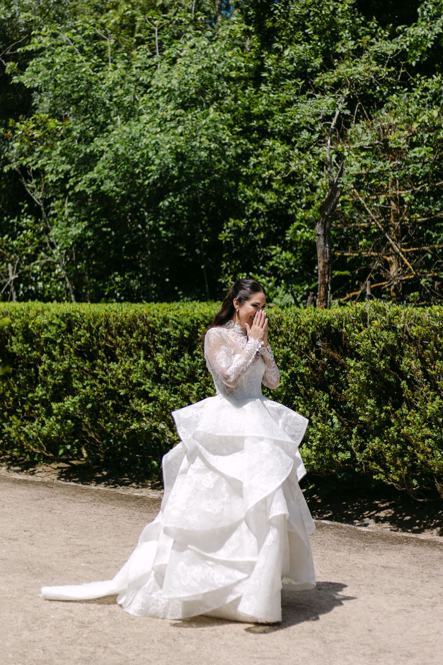 Bride in flowing white dress twirling in garden setting.