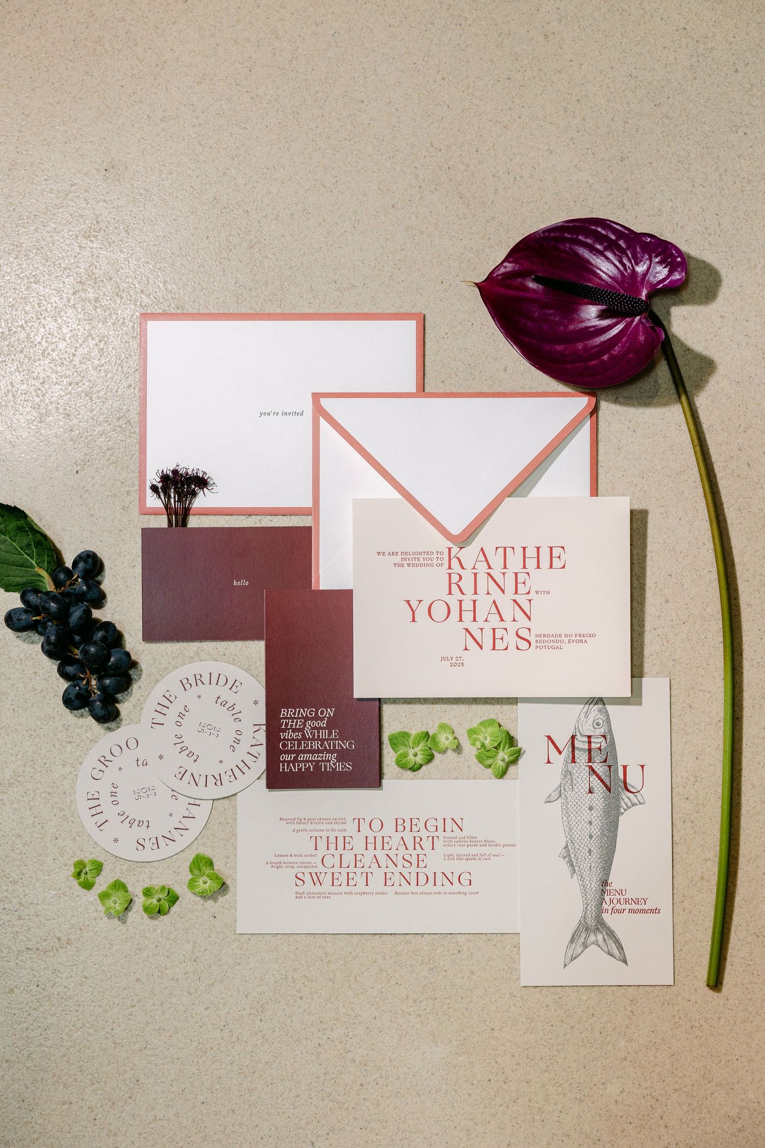 Elegant wedding invitation suite with pink envelope, menu card, and floral accents including a dark purple anthurium.