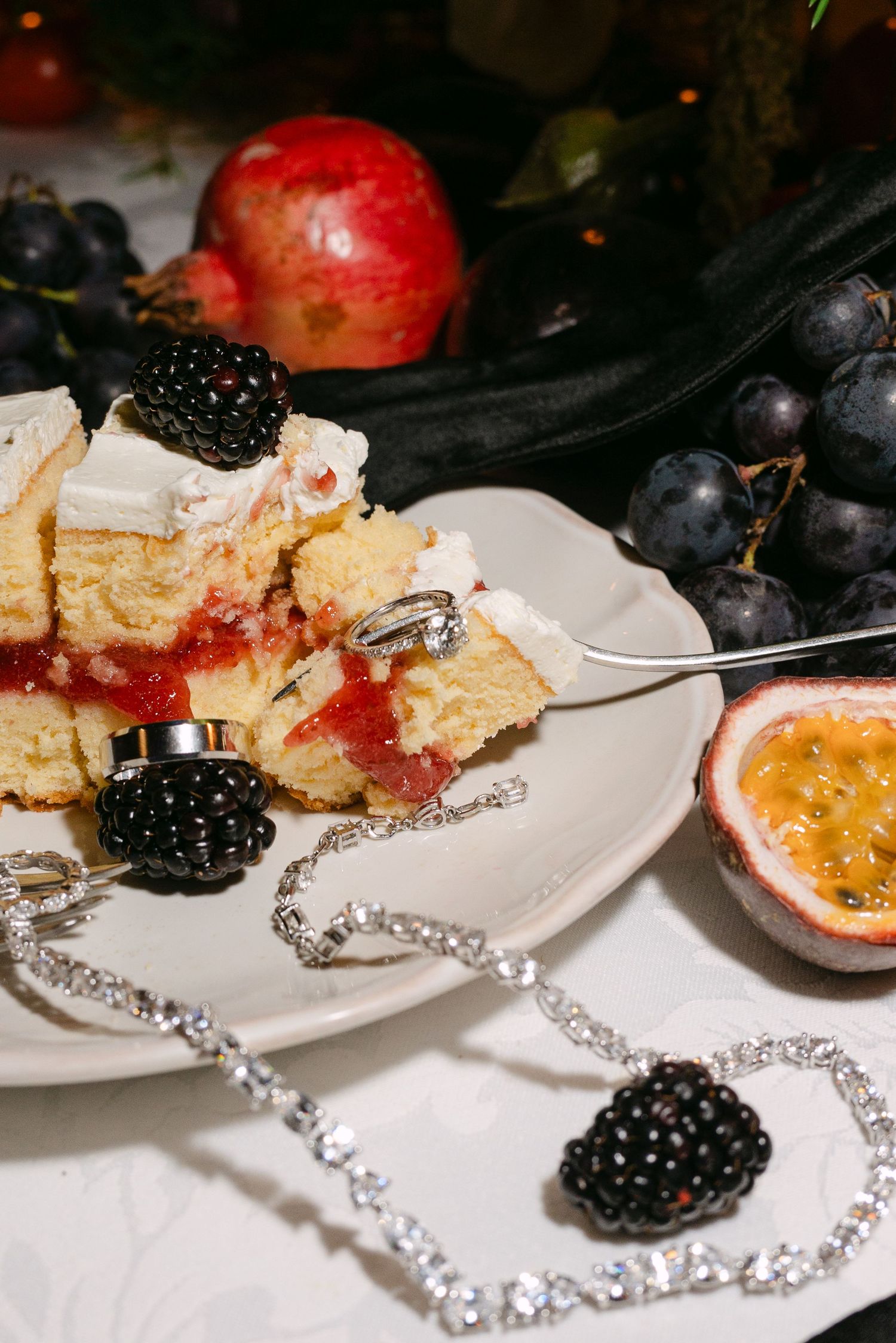 Elegant dessert plate with fresh berries, cake, and a crystal necklace as decoration.