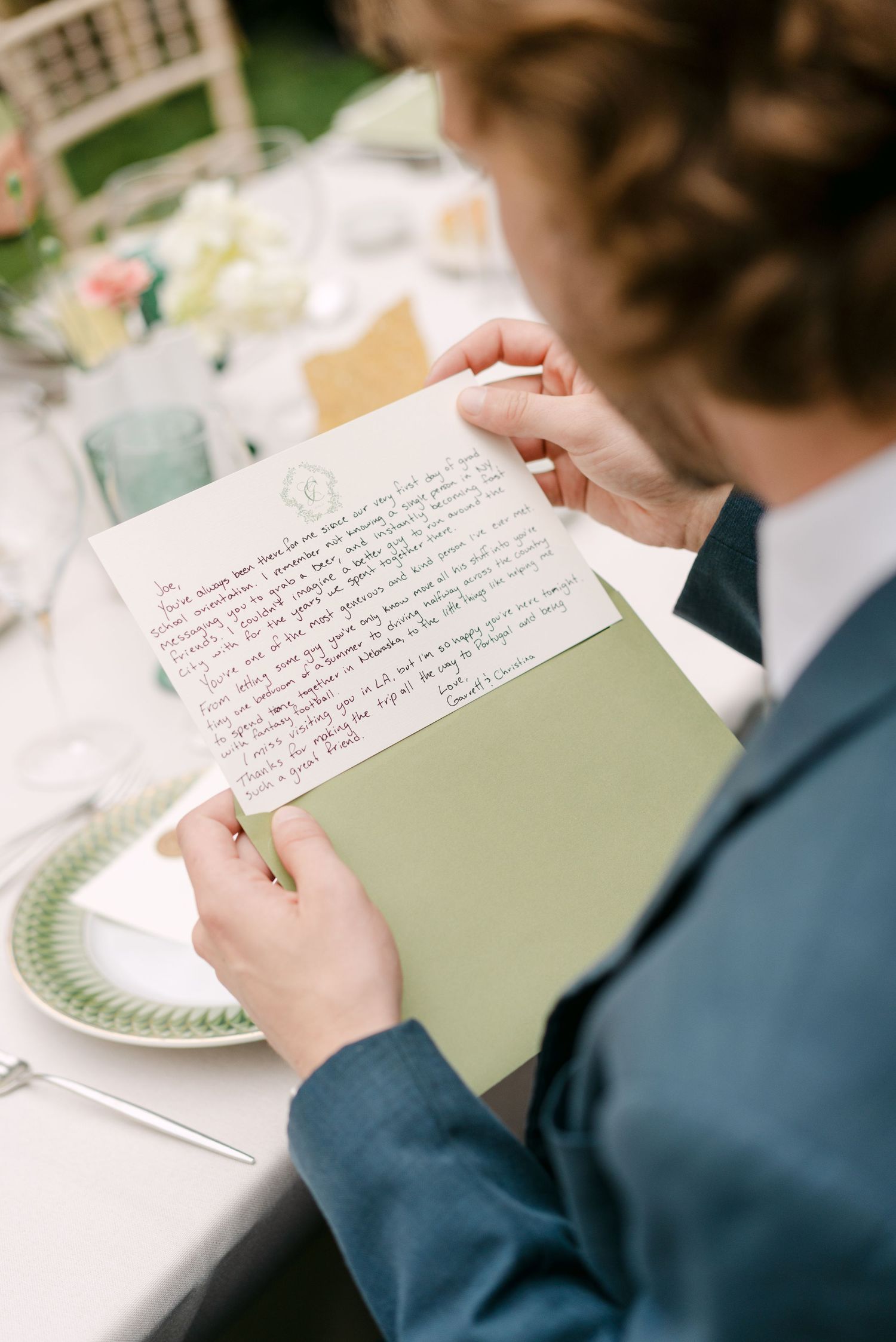 Close-up of handwritten wedding vows on sage green paper at reception table.