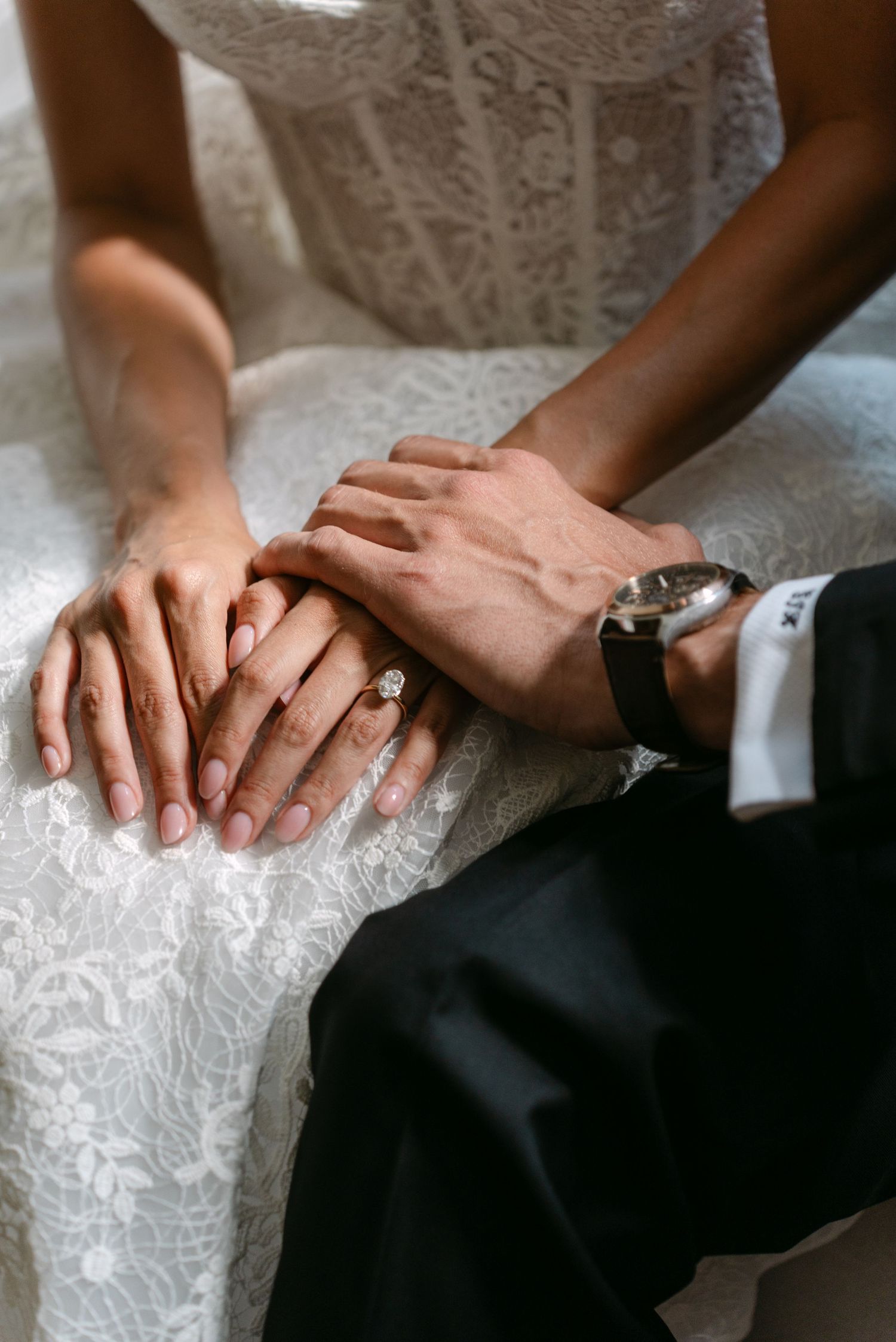 Close-up shots of hands with wedding rings resting on white lace fabric.