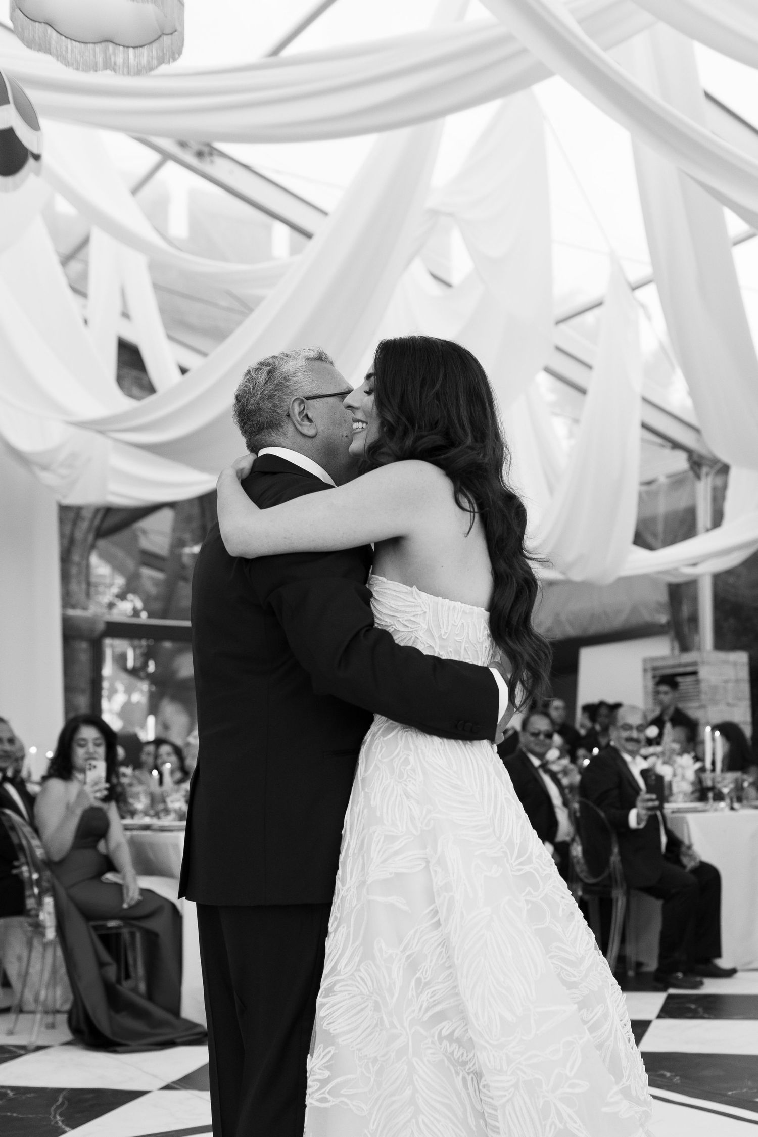 Romantic dance moment under white fabric draping at an elegant wedding reception.