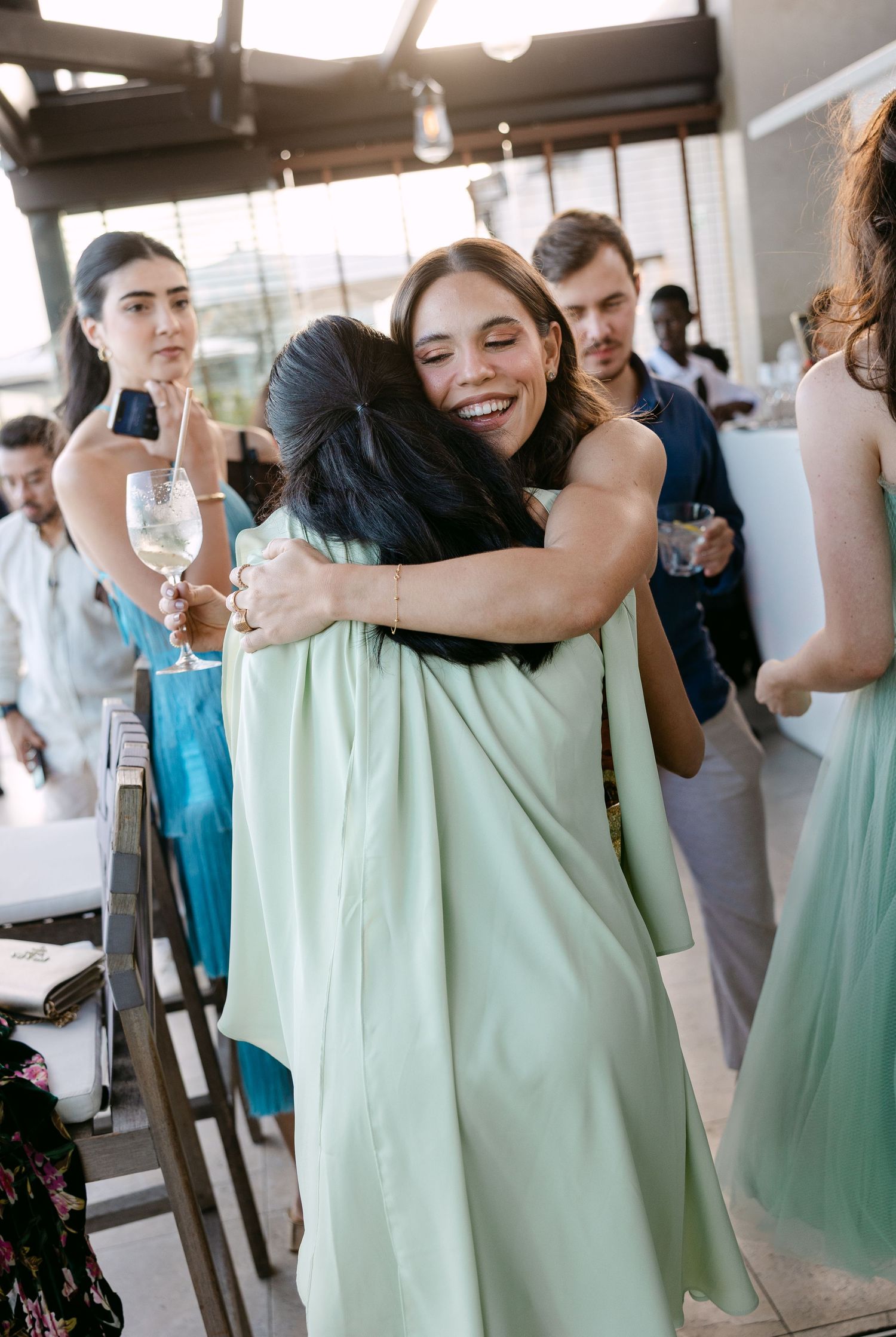 Bridesmaids in mint green dresses share emotional embraces during wedding celebrations.