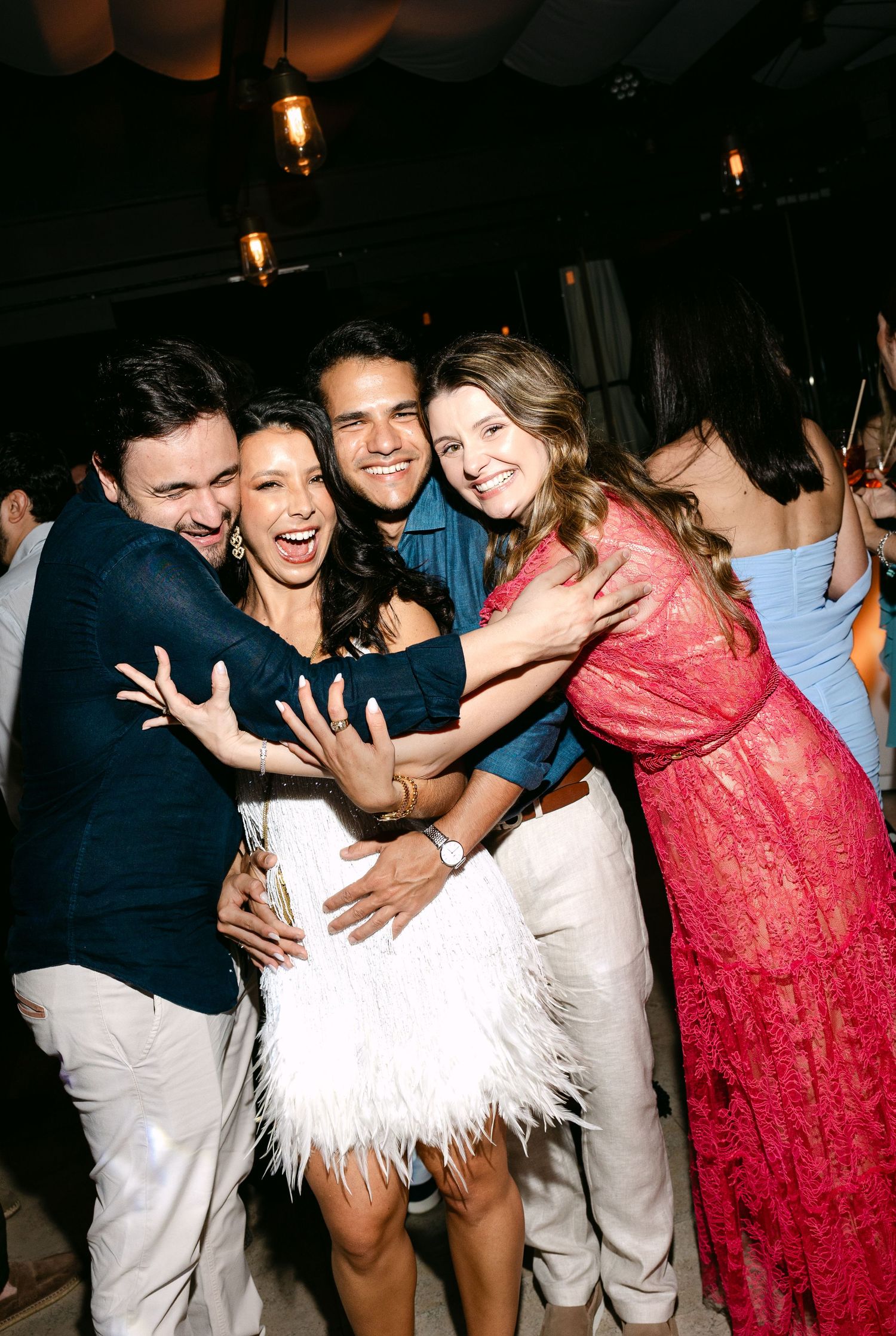 Wedding party celebrating with joyful group hugs and dancing at reception.