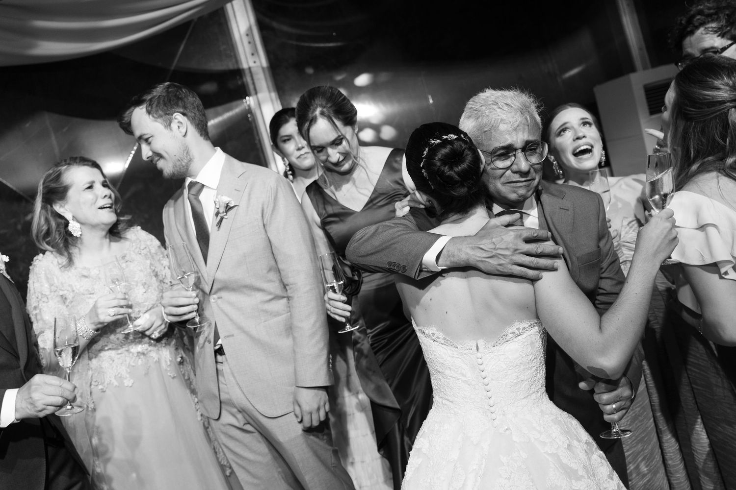 Wedding guests dancing and celebrating together on a dimly lit dance floor.