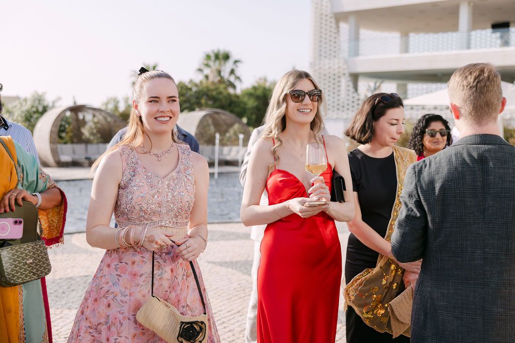 Group of people mingling at an outdoor event wearing summer dresses and formal attire.