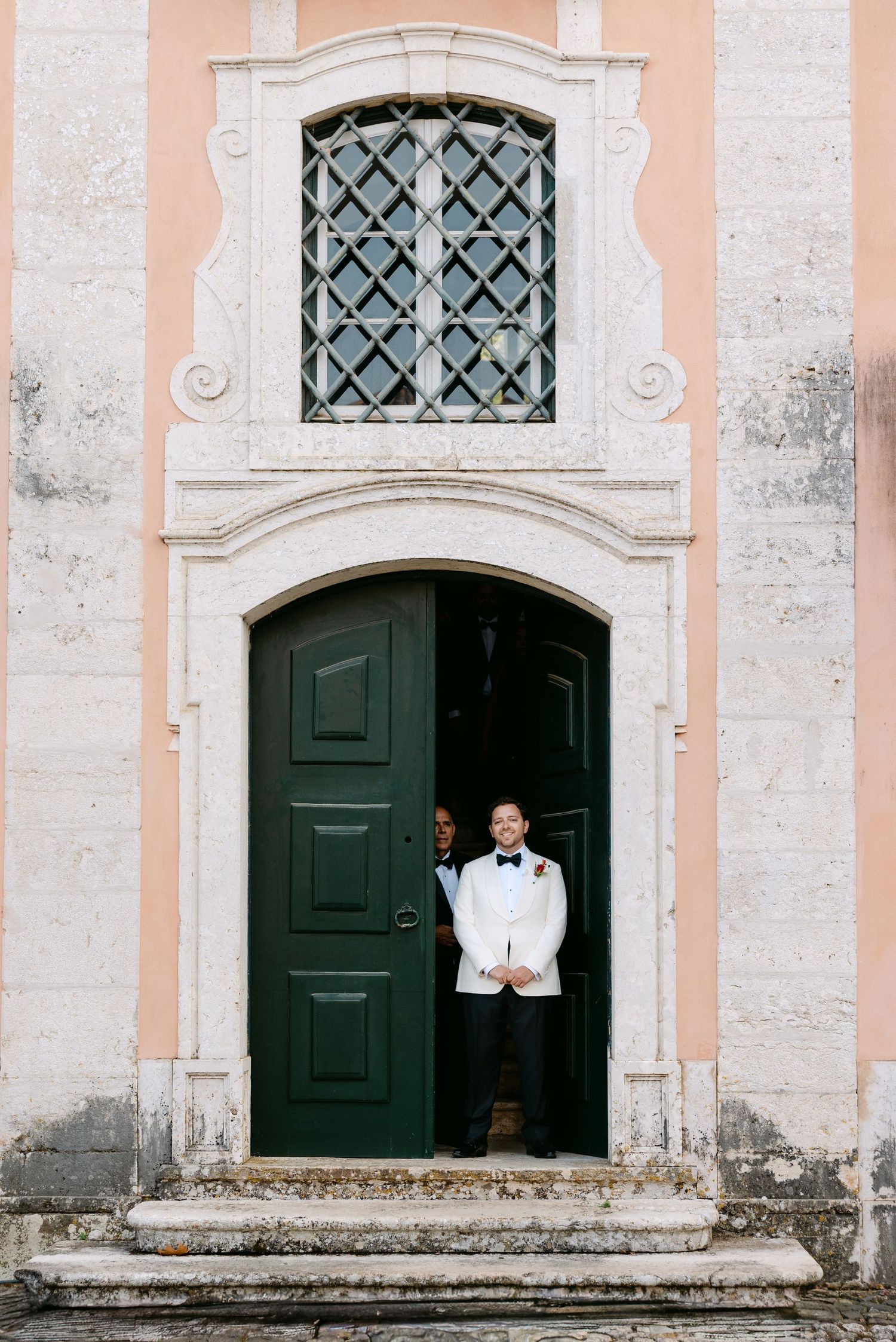 Architectural detail of palace entrance with ornate doors and windows in peach and white.