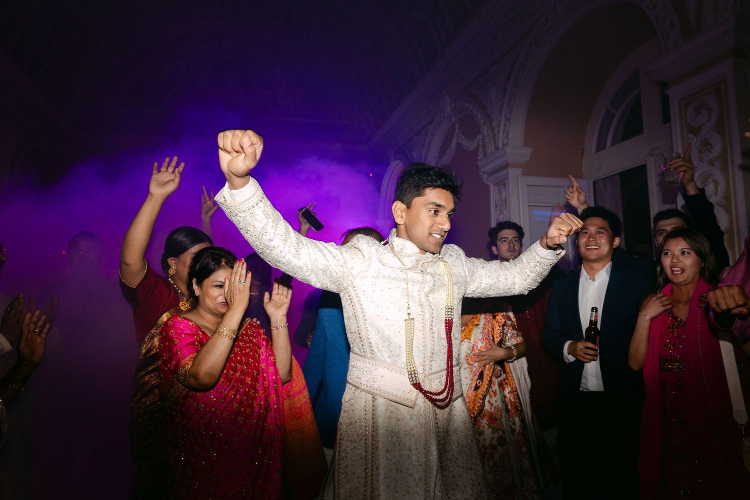 Wedding reception dance party with purple lighting and silhouettes of dancing guests.