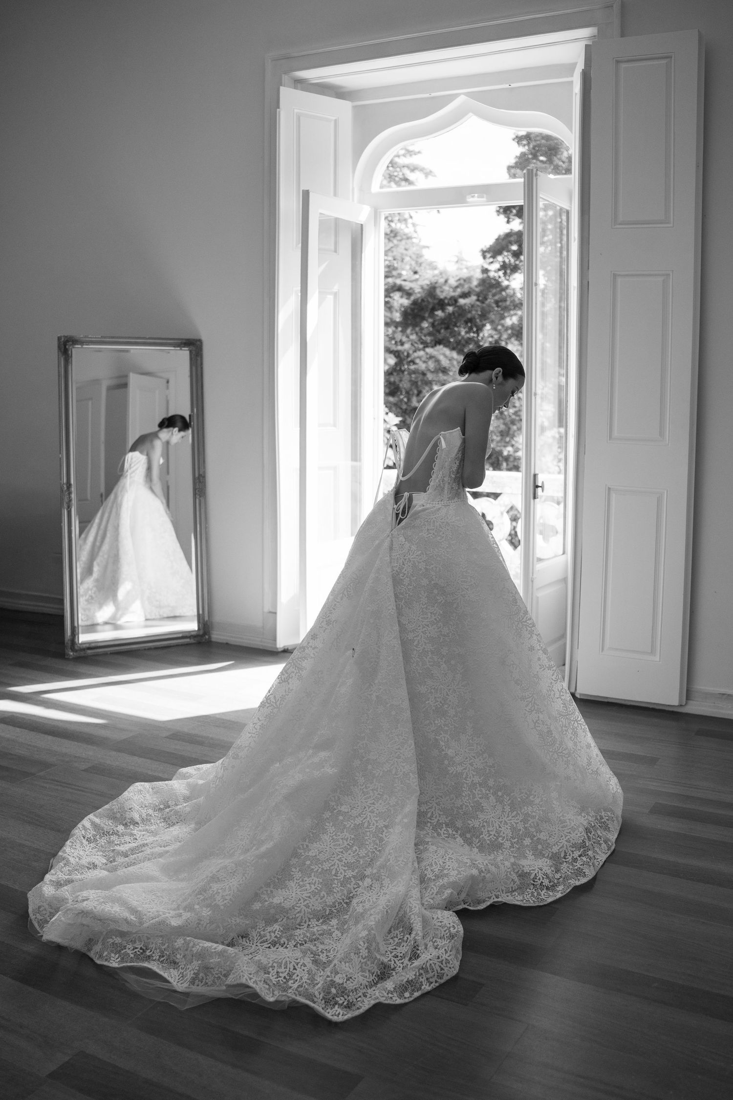 Elegant lace wedding gown with long train displayed in a bright, classic room.