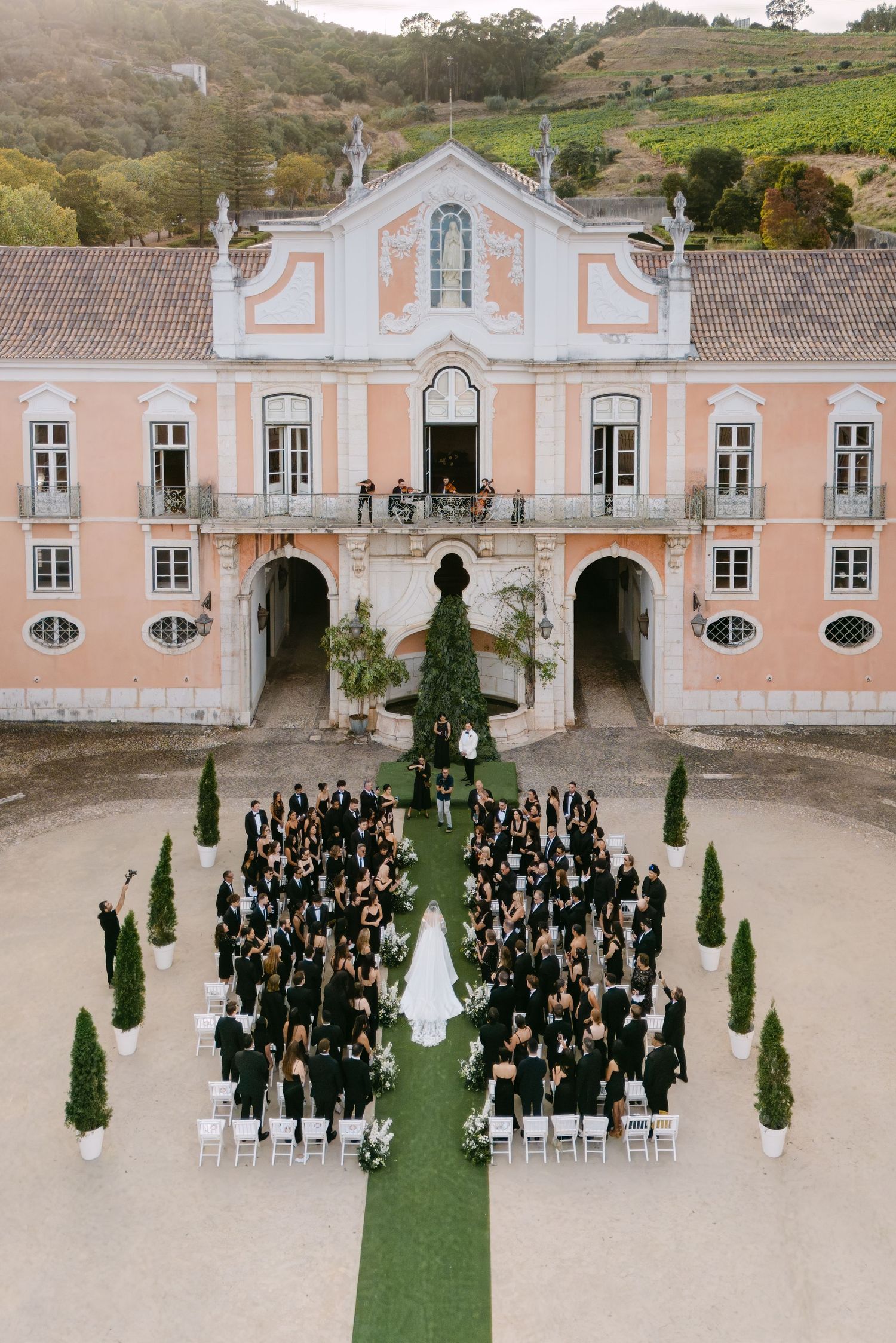 Aerial view of outdoor wedding ceremony setup in front of historic pink palace.