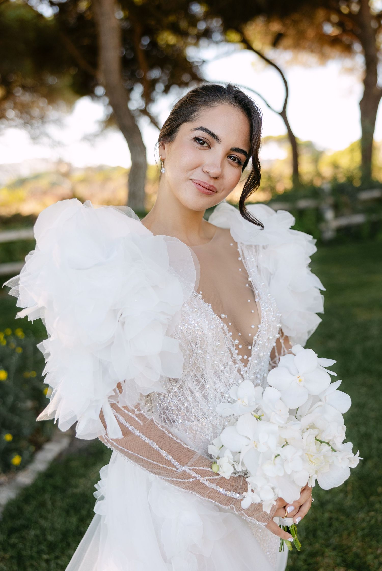 A detailed view of a luxurious white wedding gown with feather accents and floral bouquet.