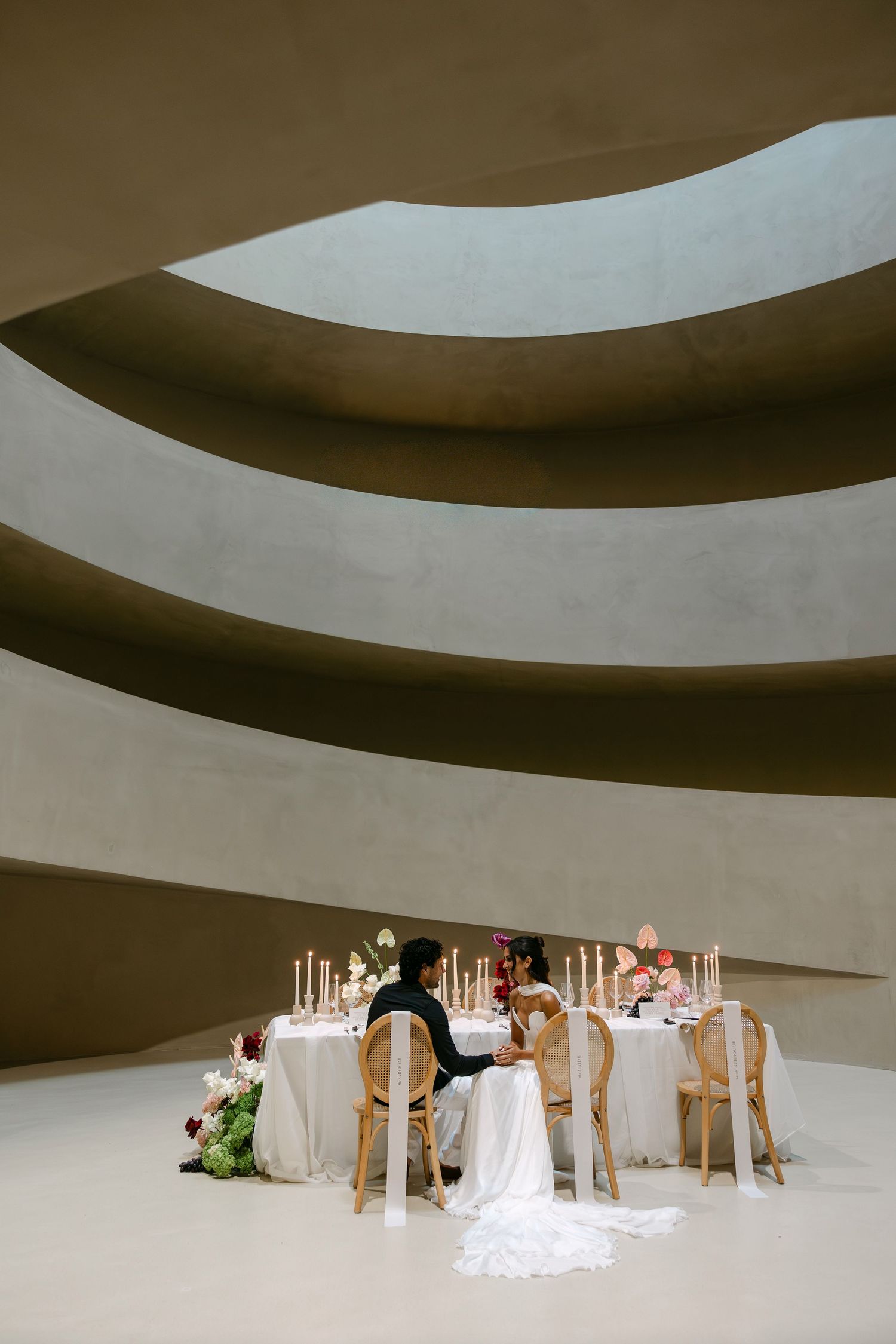 Couple seated at elegant wedding sweetheart table inside the spiral rotunda of the Guggenheim Museum.